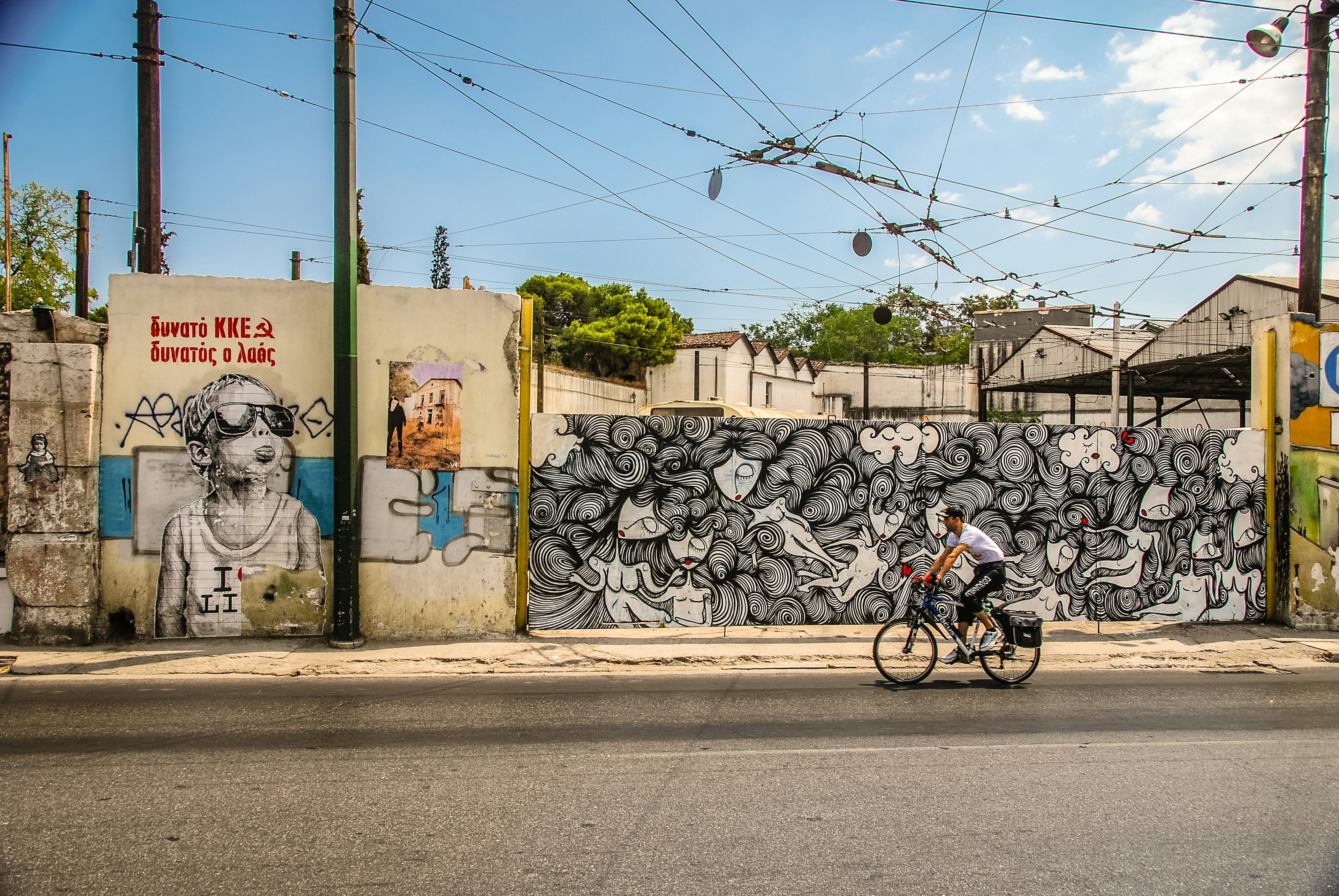 Man riding his bike past colourful grafitti in central Athens