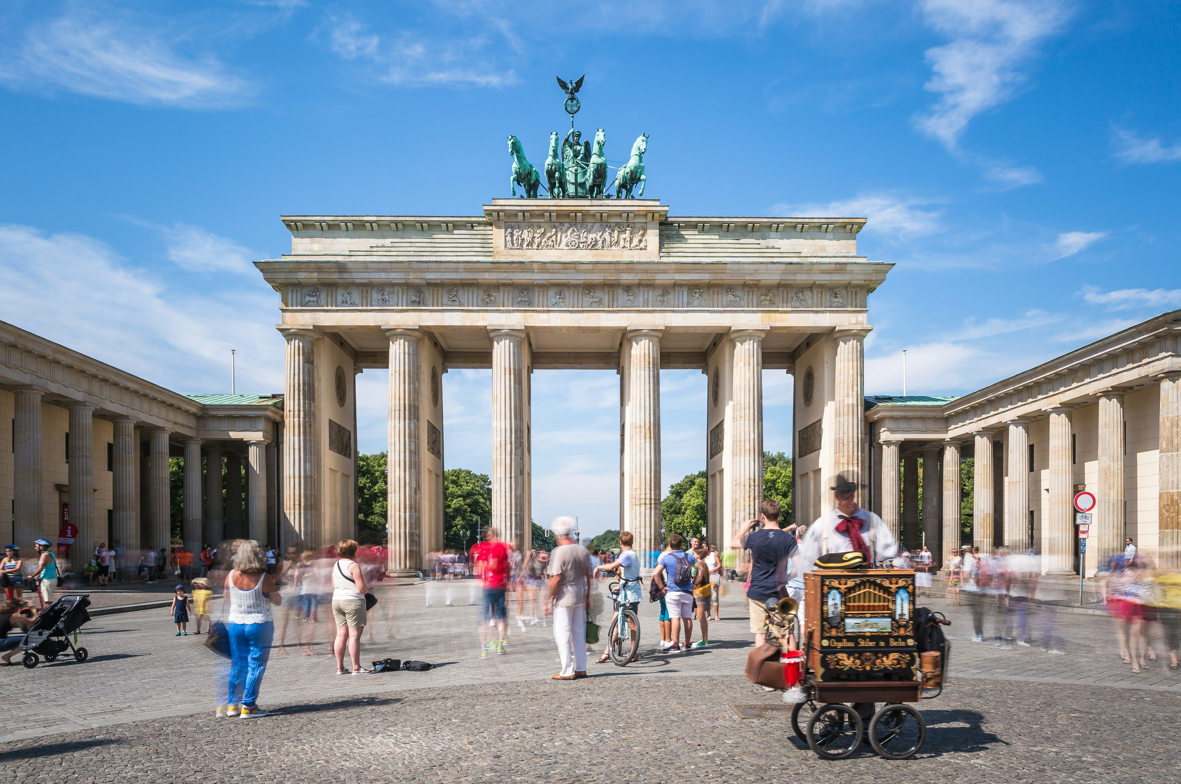 Brandenburg gate in Berlin on a sunny day with a barrel organ