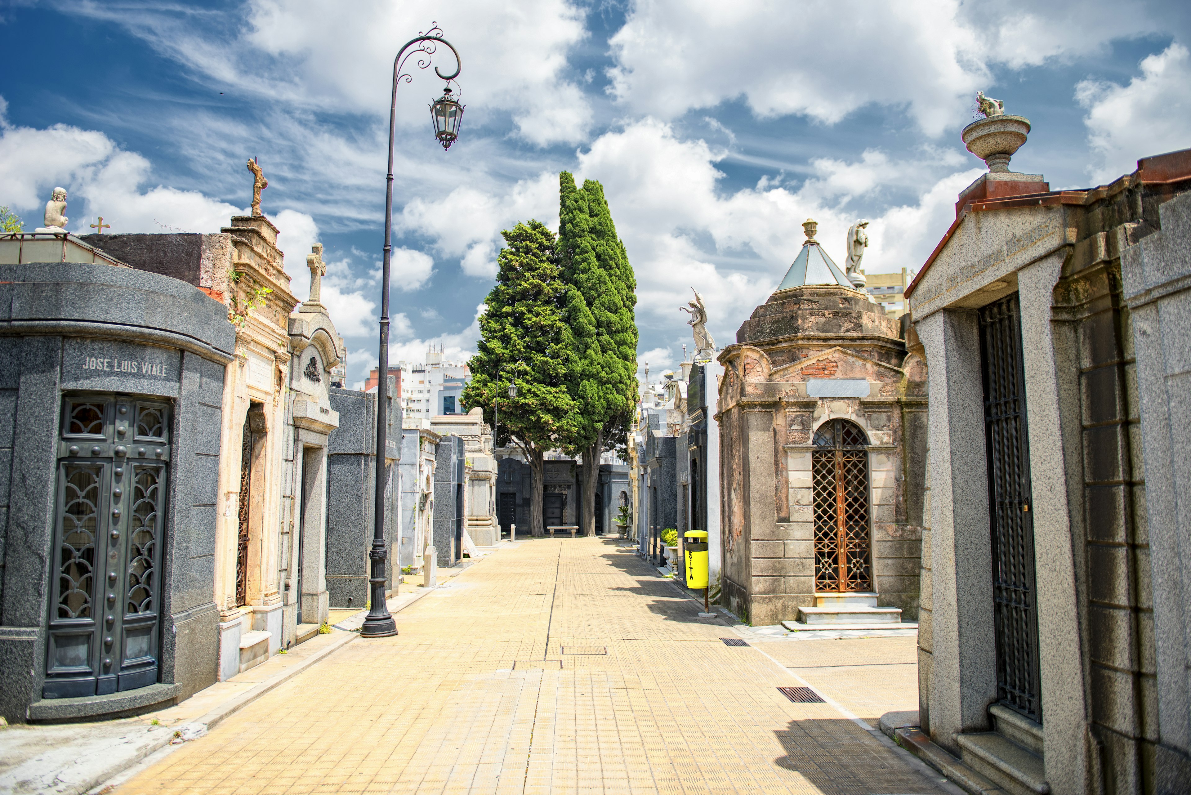 A series of stone mausoleums lining a neat pathway under a blue sky