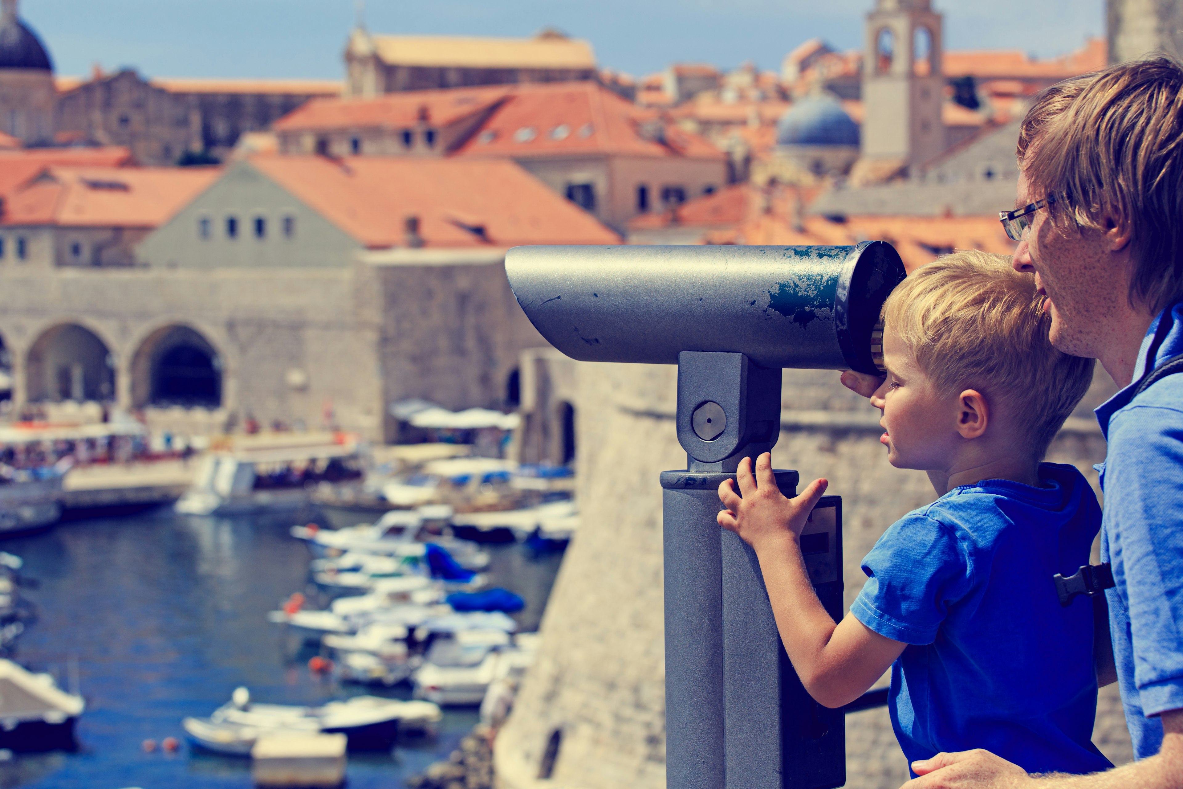 A man and small boy looking through binoculars at the rooftops of Dubrovnik