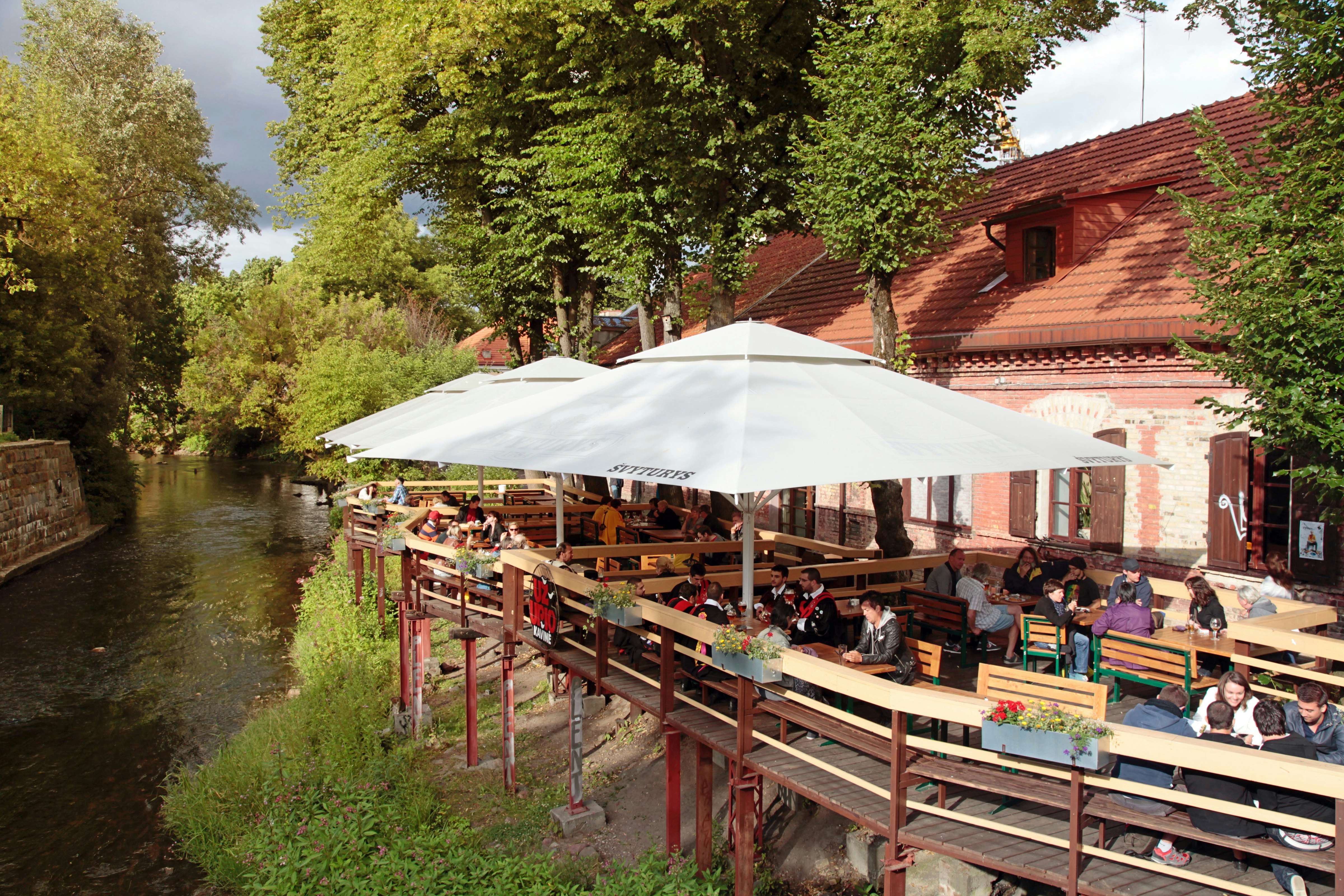 People relaxing on cafe terrace near River Vilnele in Republic of Uzupio (Uzupis) neighborhood, Vilnius, Lithuania.