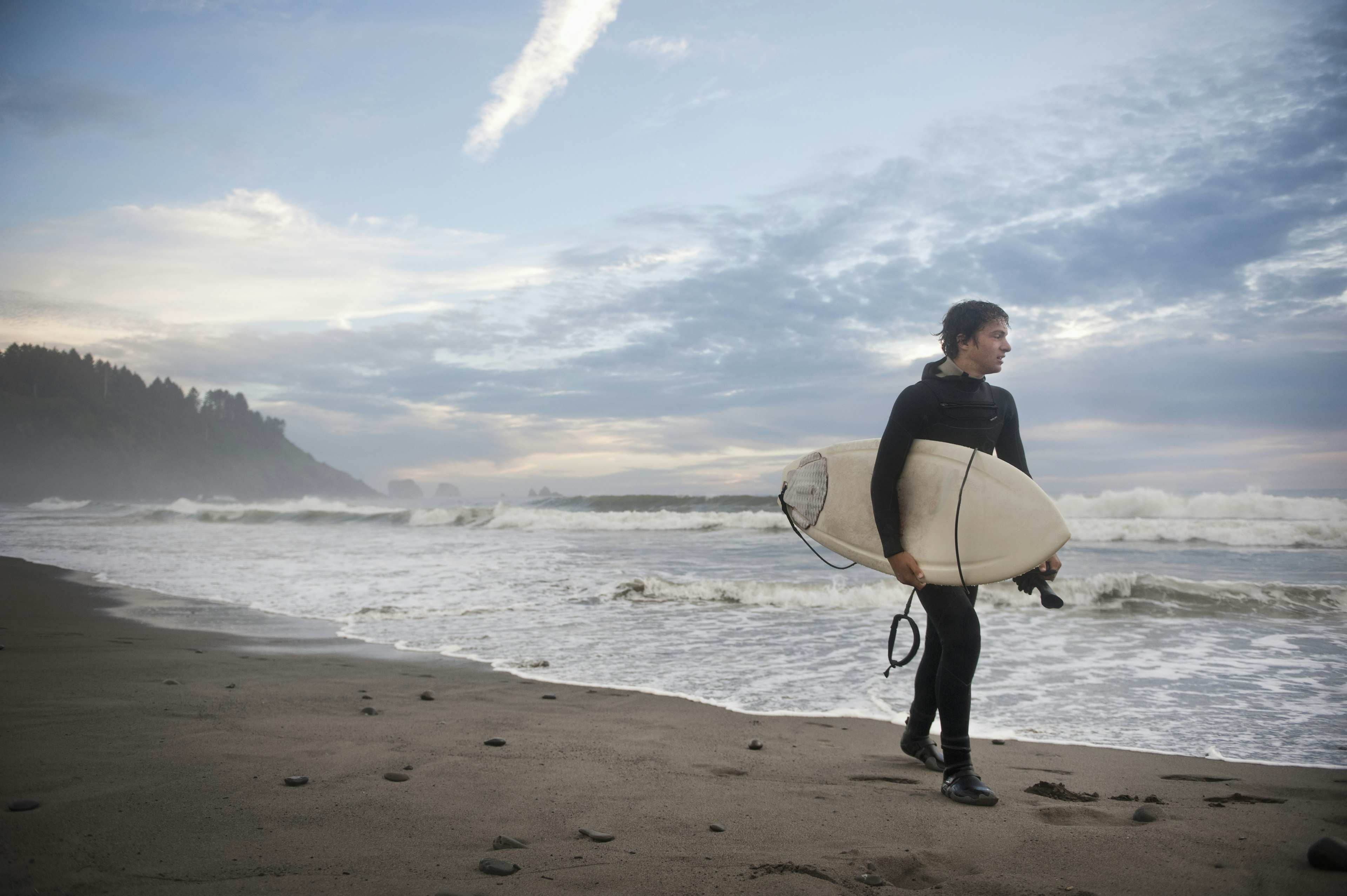 A Young Man Carries His Surfboard Down The Beach; La Push Washington United States Of America