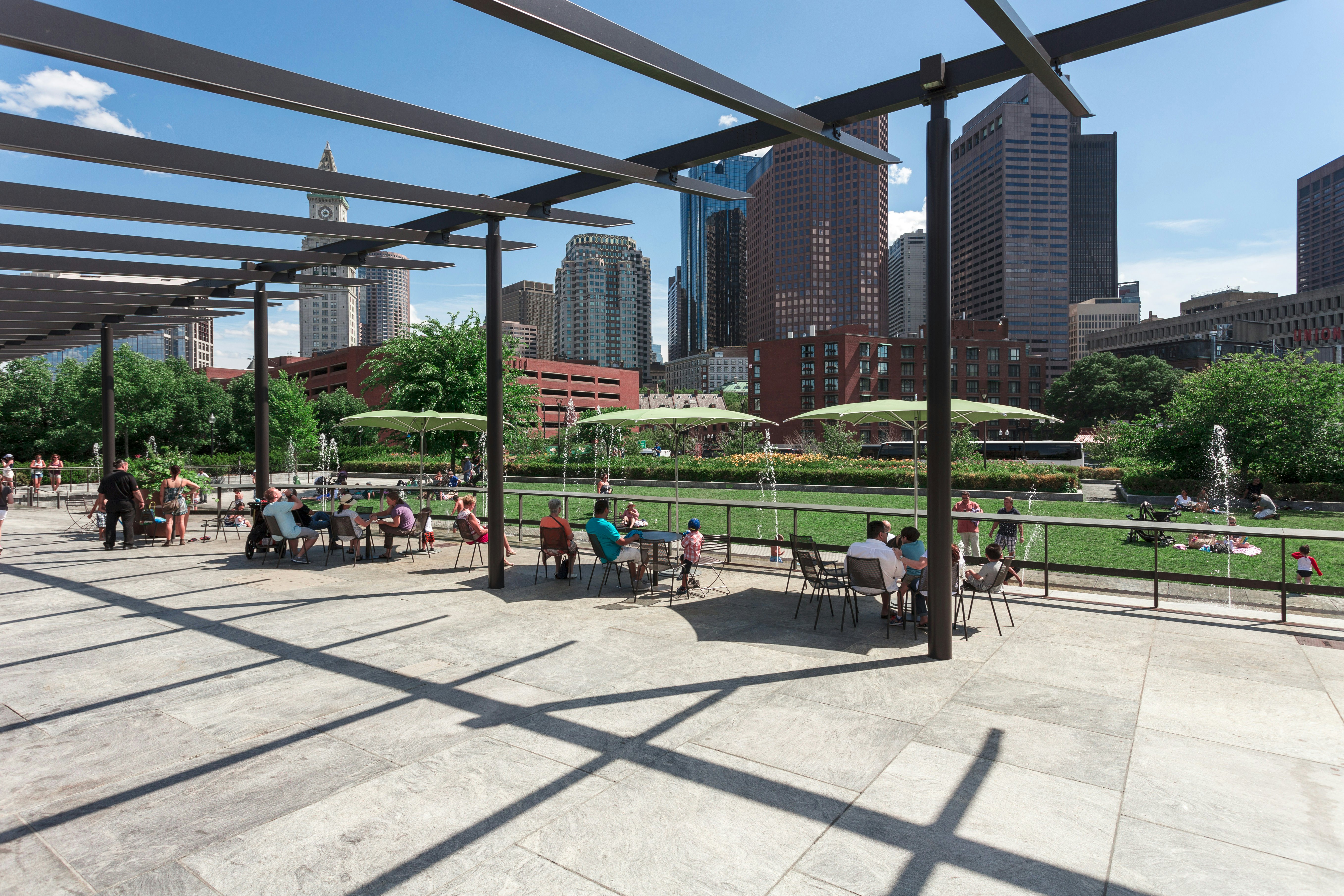 People sitting at tables under umbrellas at the Rose Fitzgerald Kennedy Greenway's North End Park