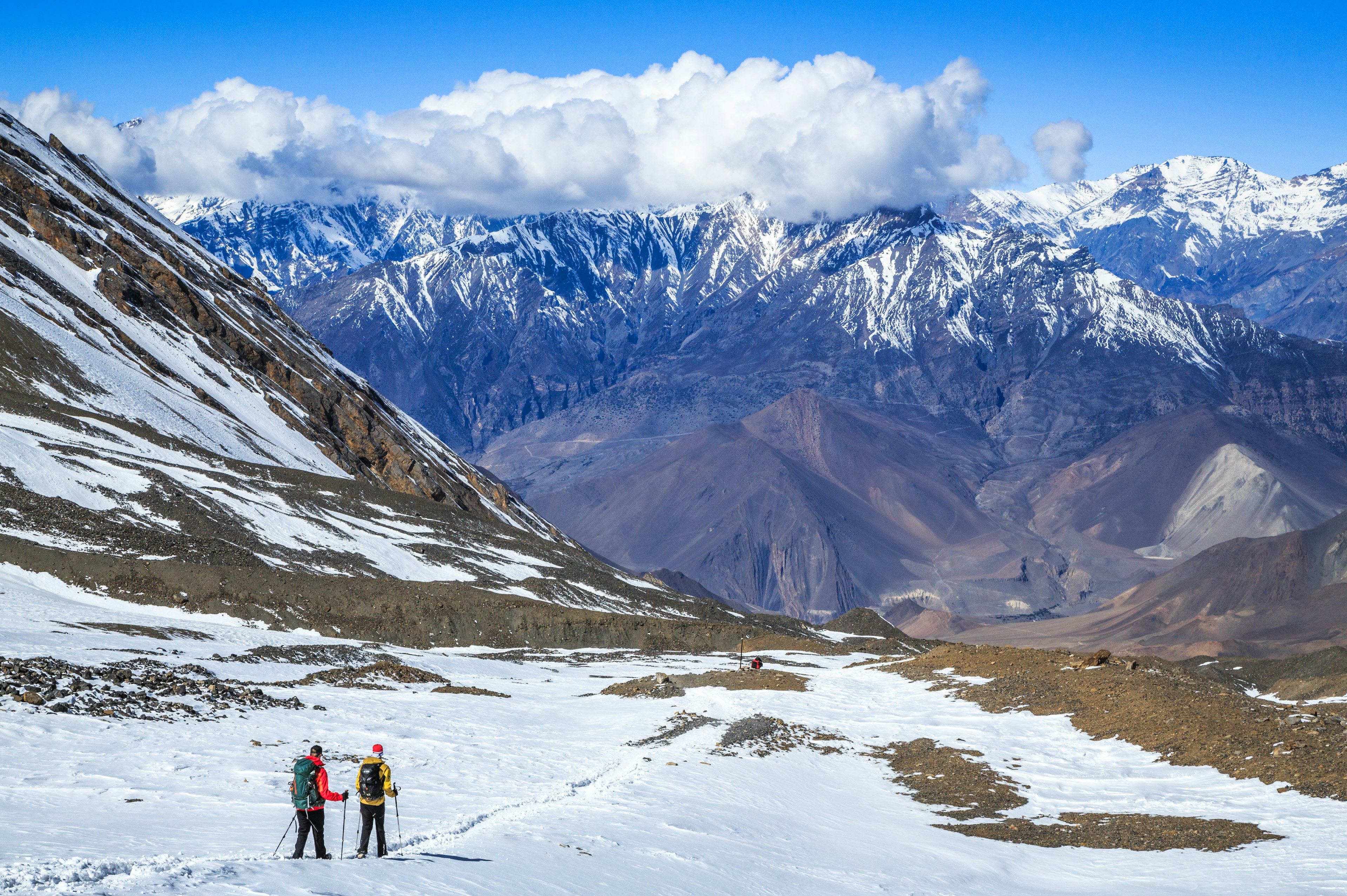 Two trekkers descend from the Thorung La pass on the Annapurna Circuit Trek