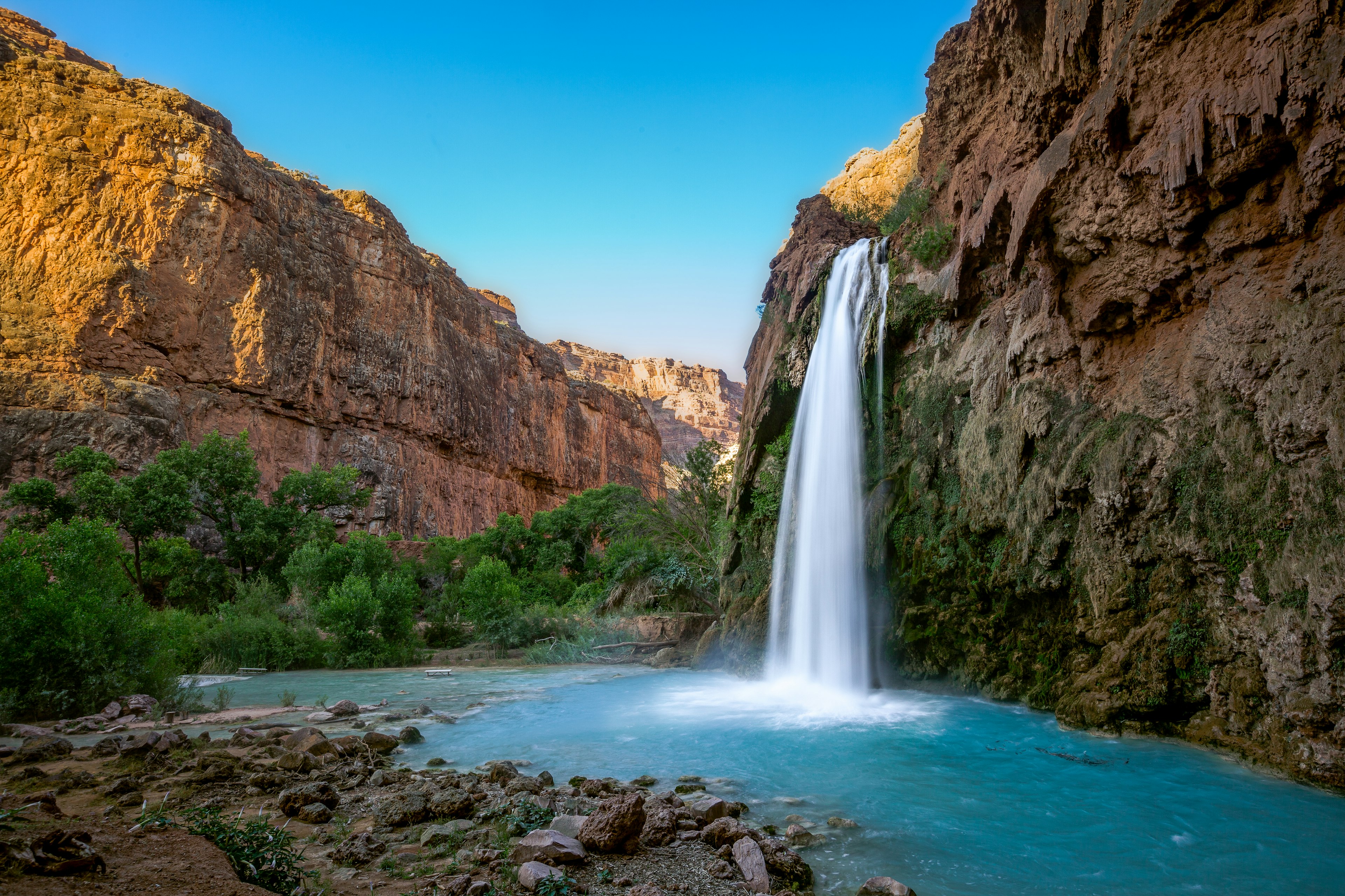 A waterfall into a turquoise pool surrounded by red rocks