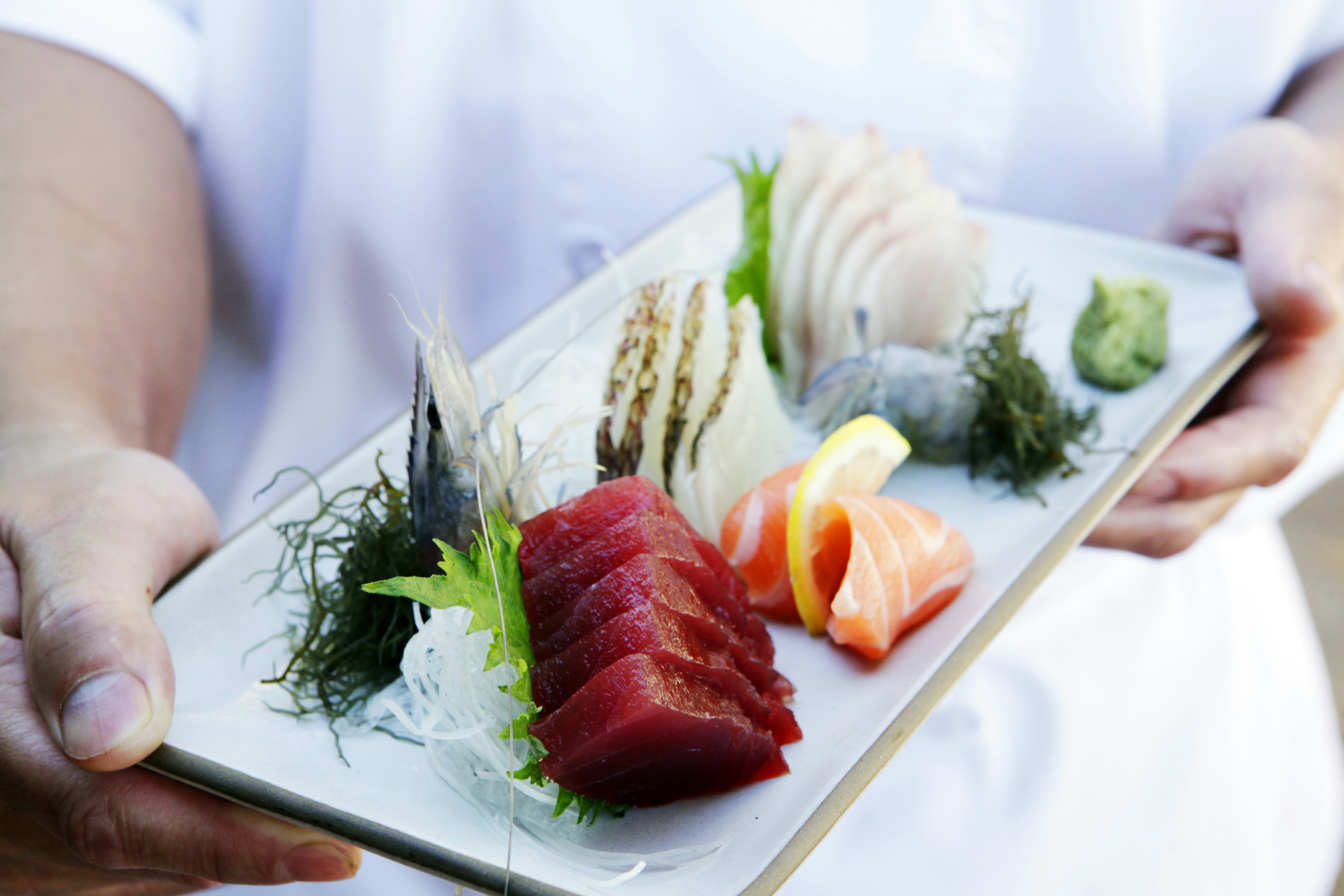 Hands holding tray of fresh sushi