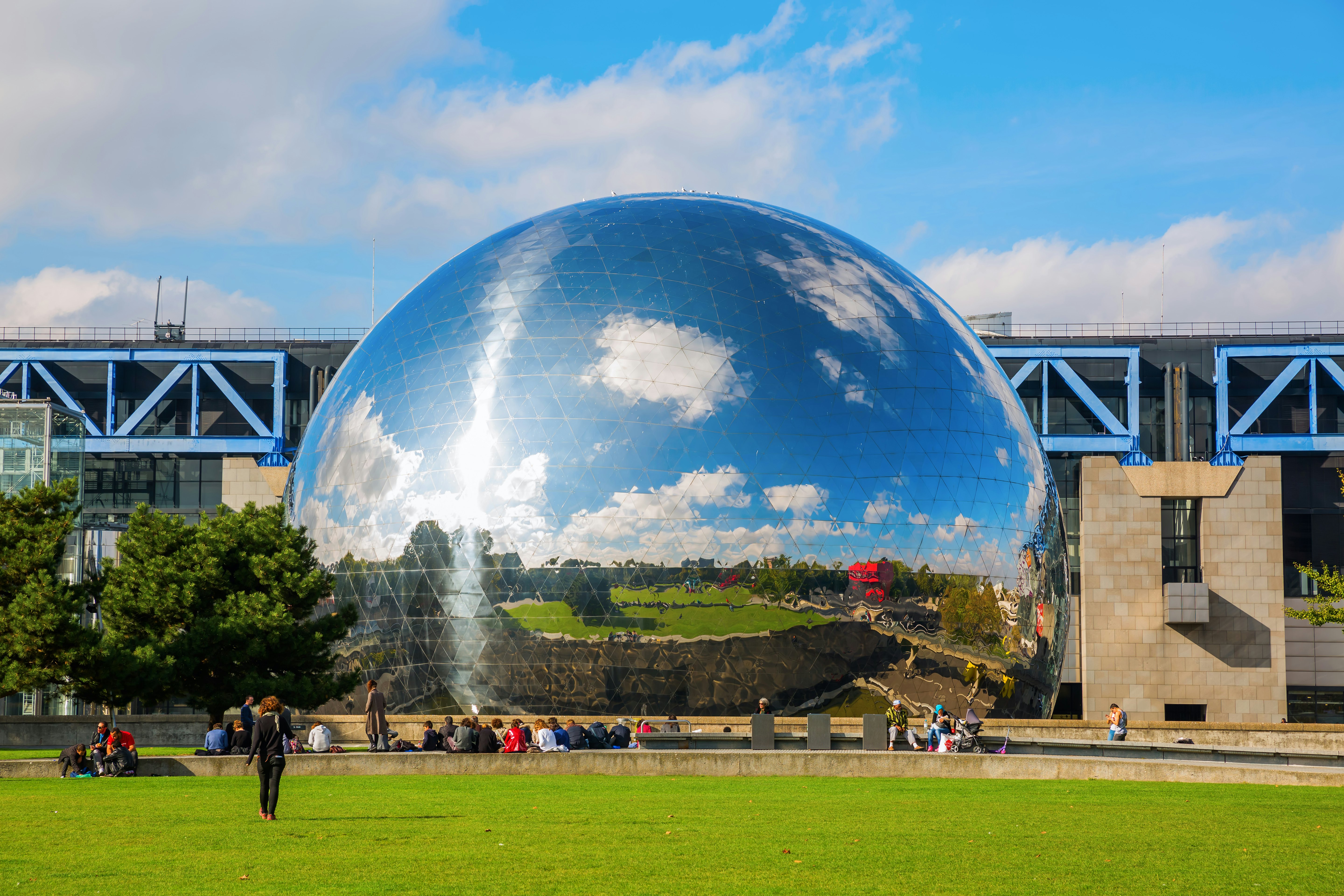 A mirror-finished geodesic dome sits in a lush, green park.