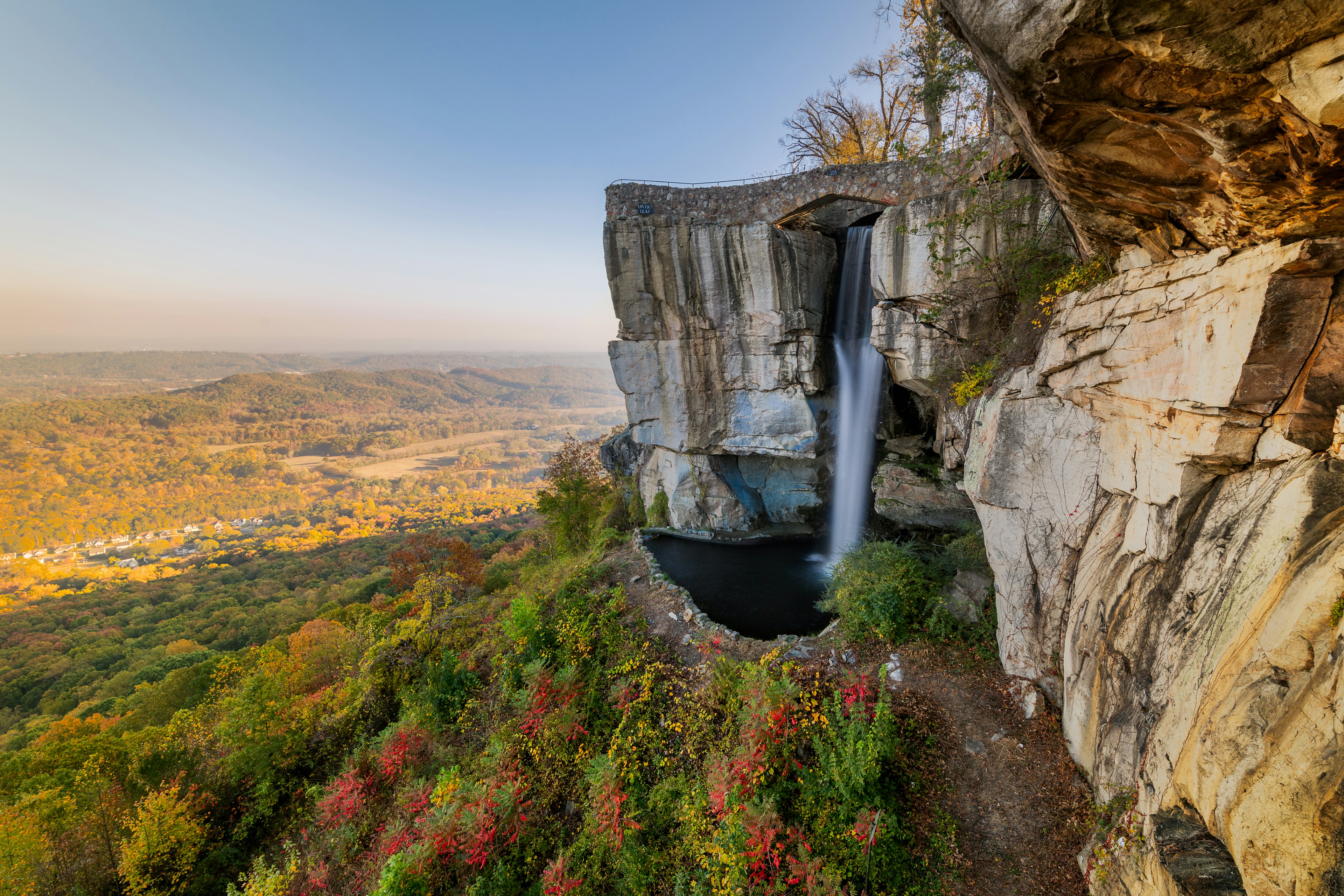 A waterfall from a rocky outcrop surrounded by trees in autumn colors