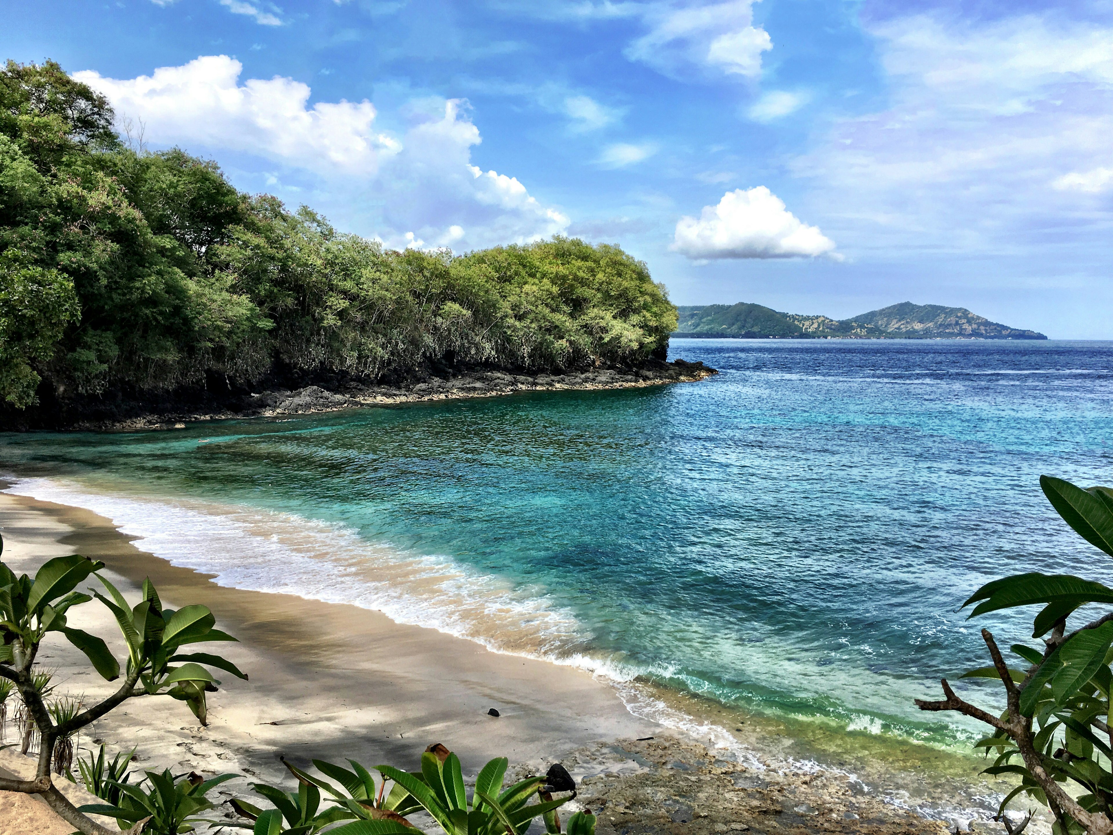 Empty sands of Blue Lagoon Beach surrounded by trees in Bali, Indonesia