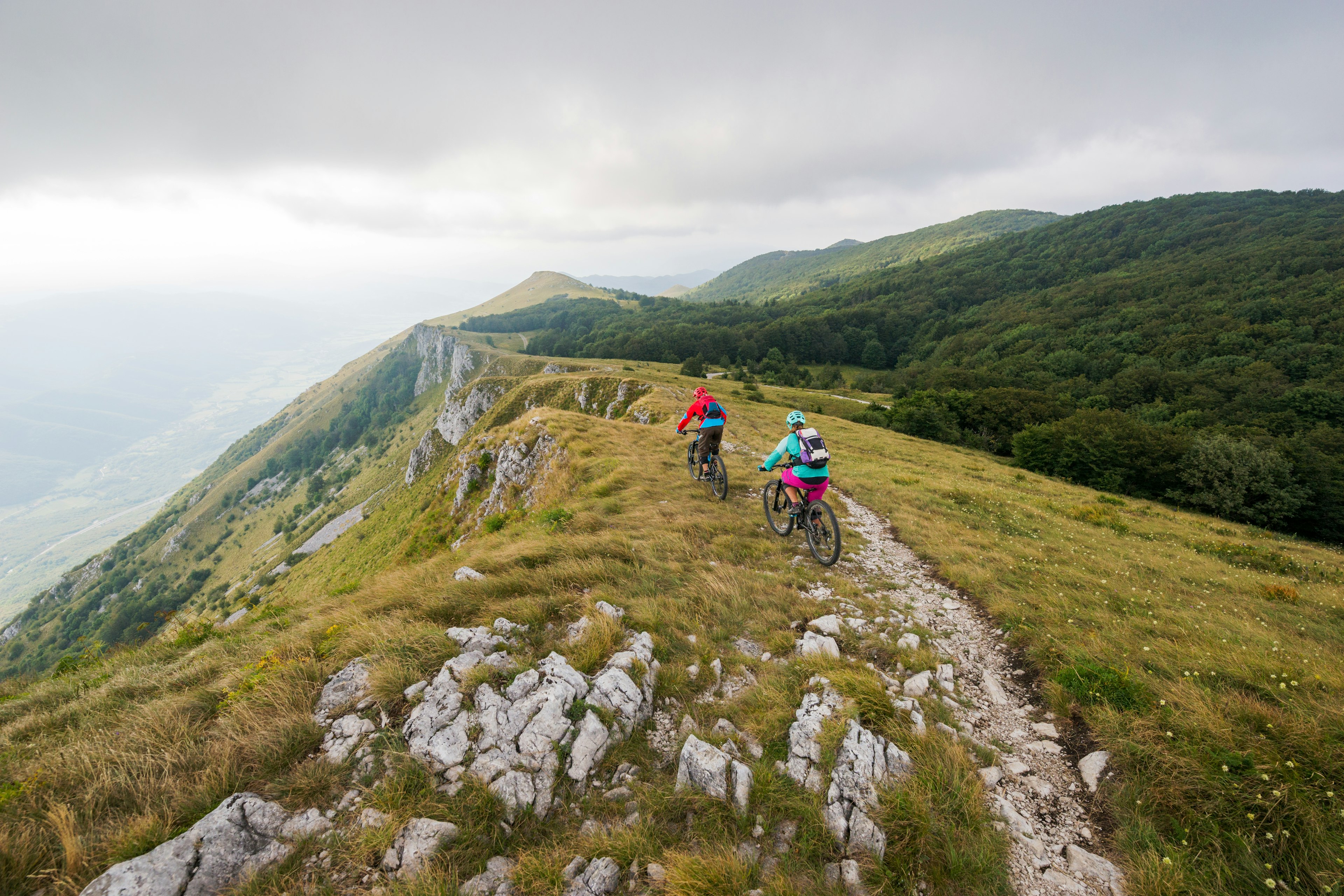 Two people mountain biking on a clifftop trail