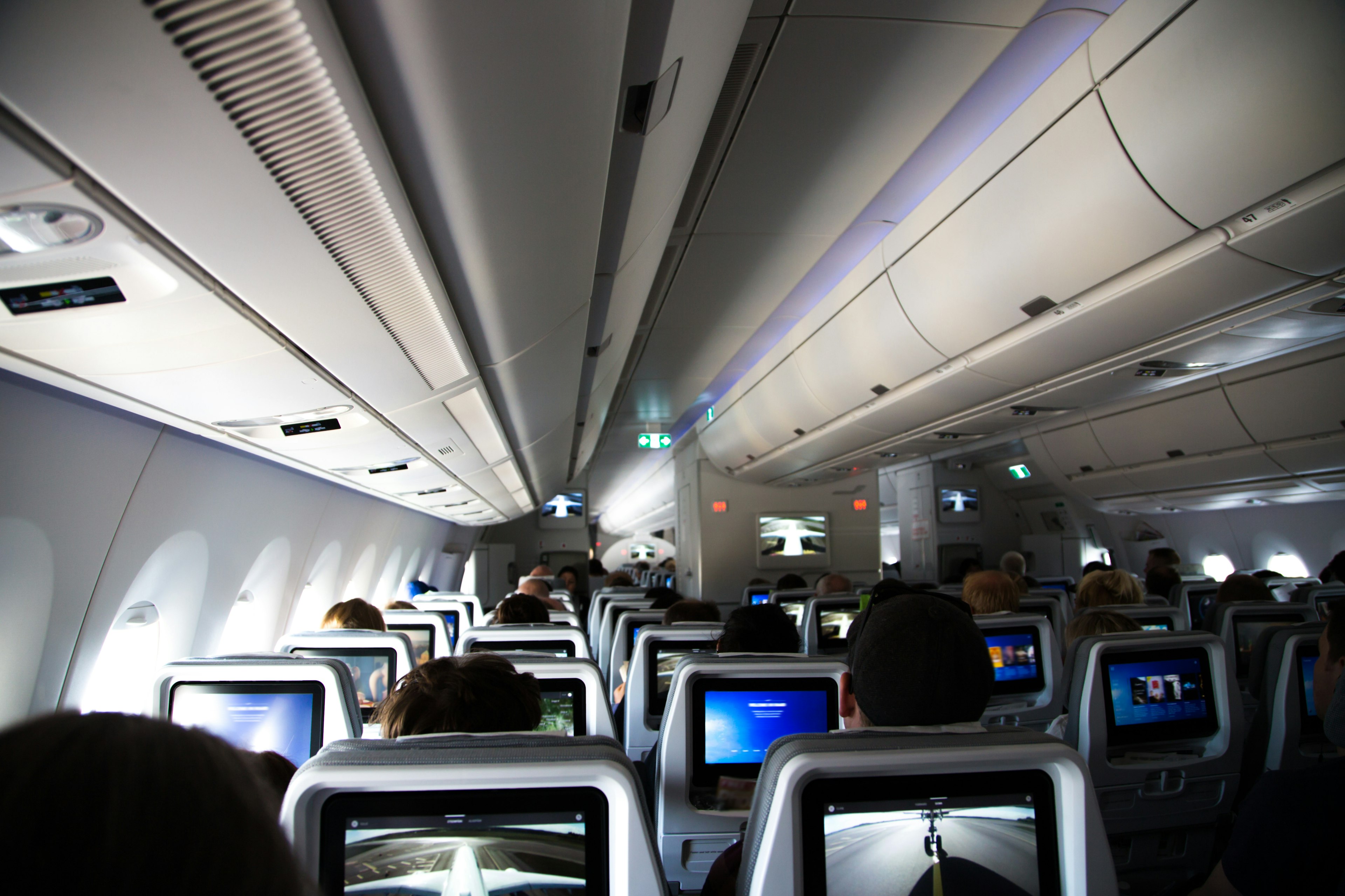 Inside of a long distance new airplane with passengers sitting and resting during a long flight with picture taken from the back of the airplane.