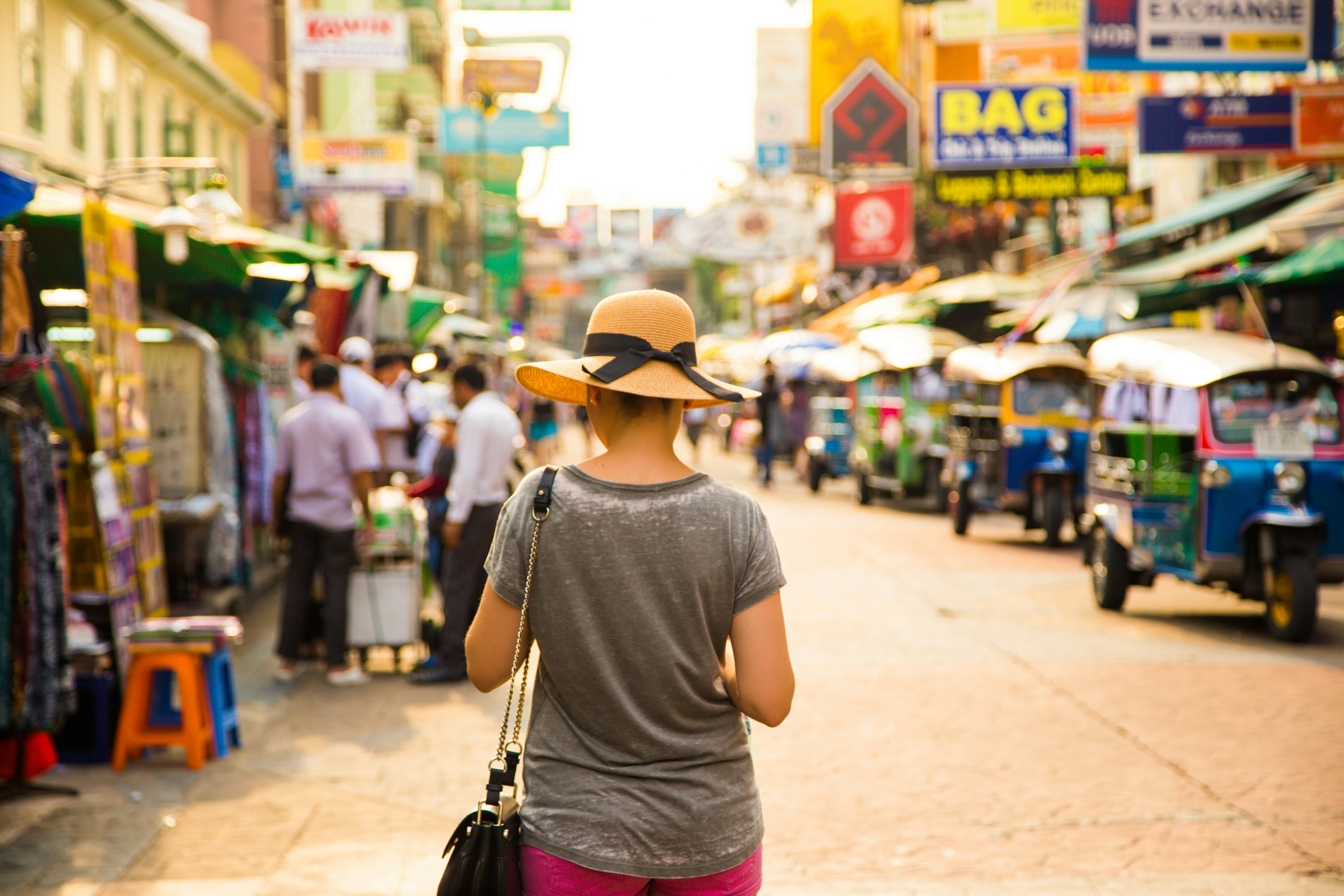 Traveler girl with hat protecting from strong sun in the bustle city of Bangkok during travel vacations.