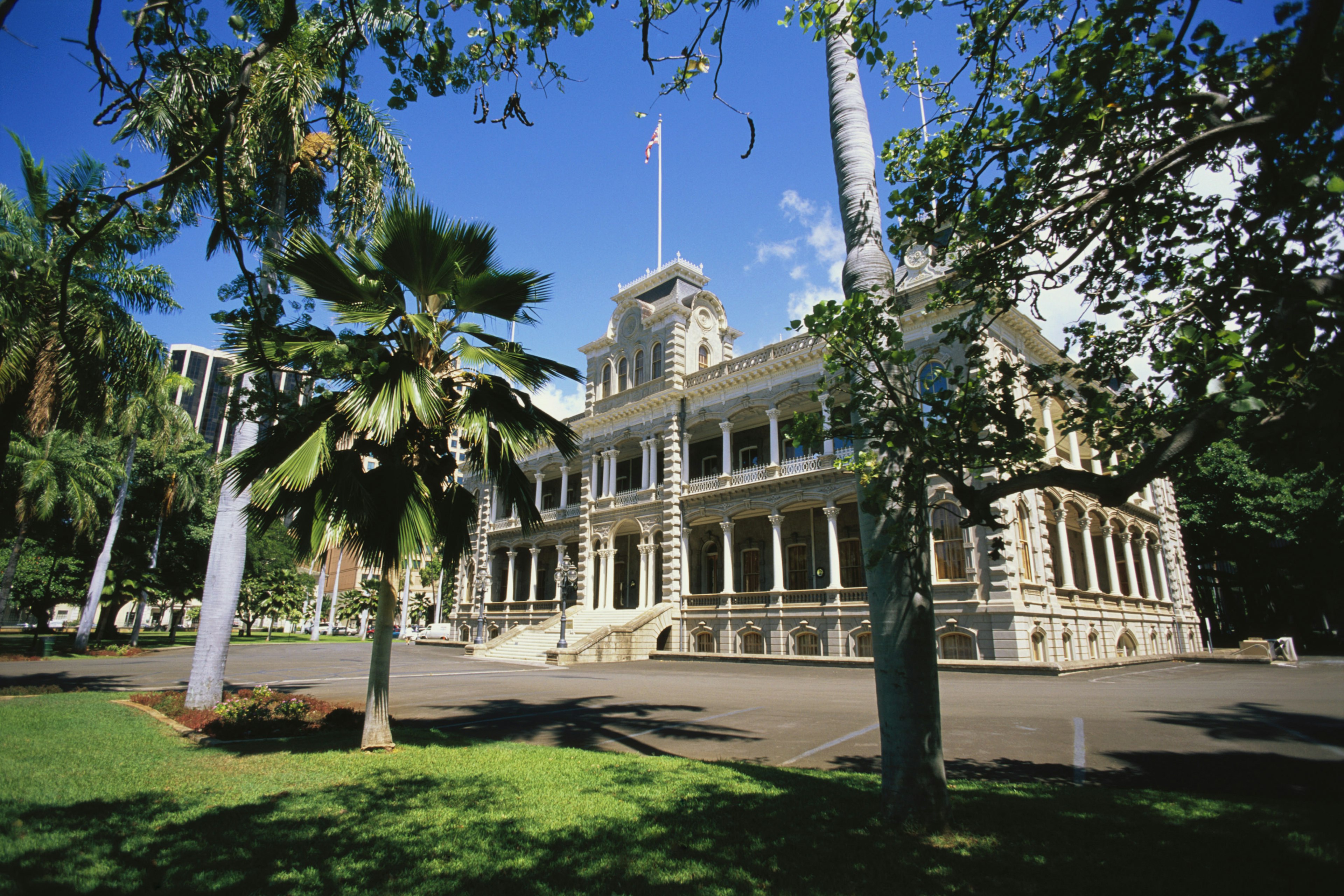 Exterior shot of a grand palace building surrounded by gardens with palm trees