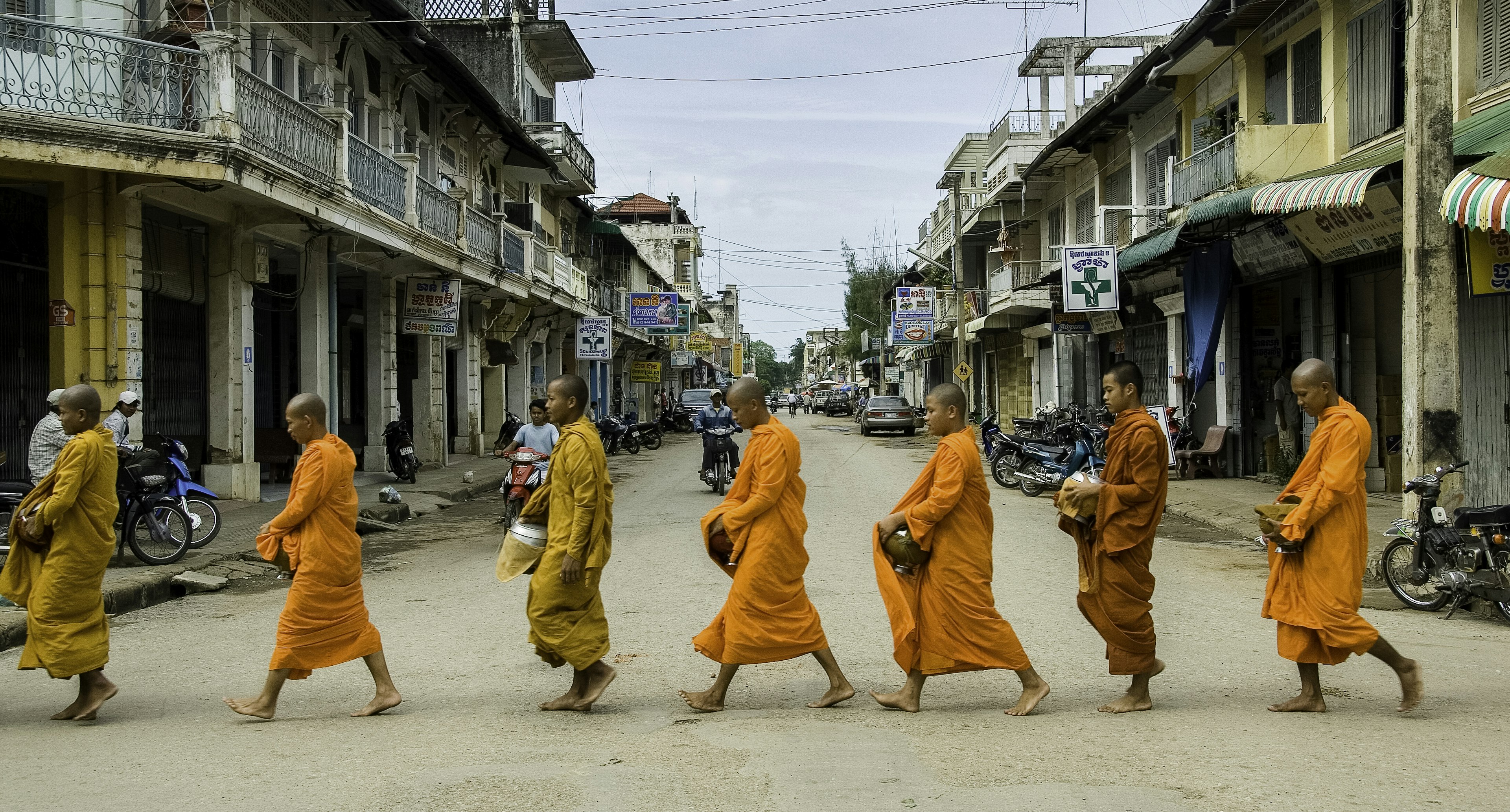 Monks walk across urban street in unison similar to Luang Prabang