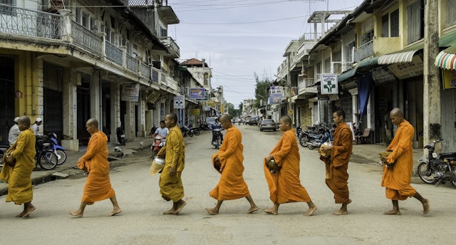Monks walk across urban street in unison similar to Luang Prabang