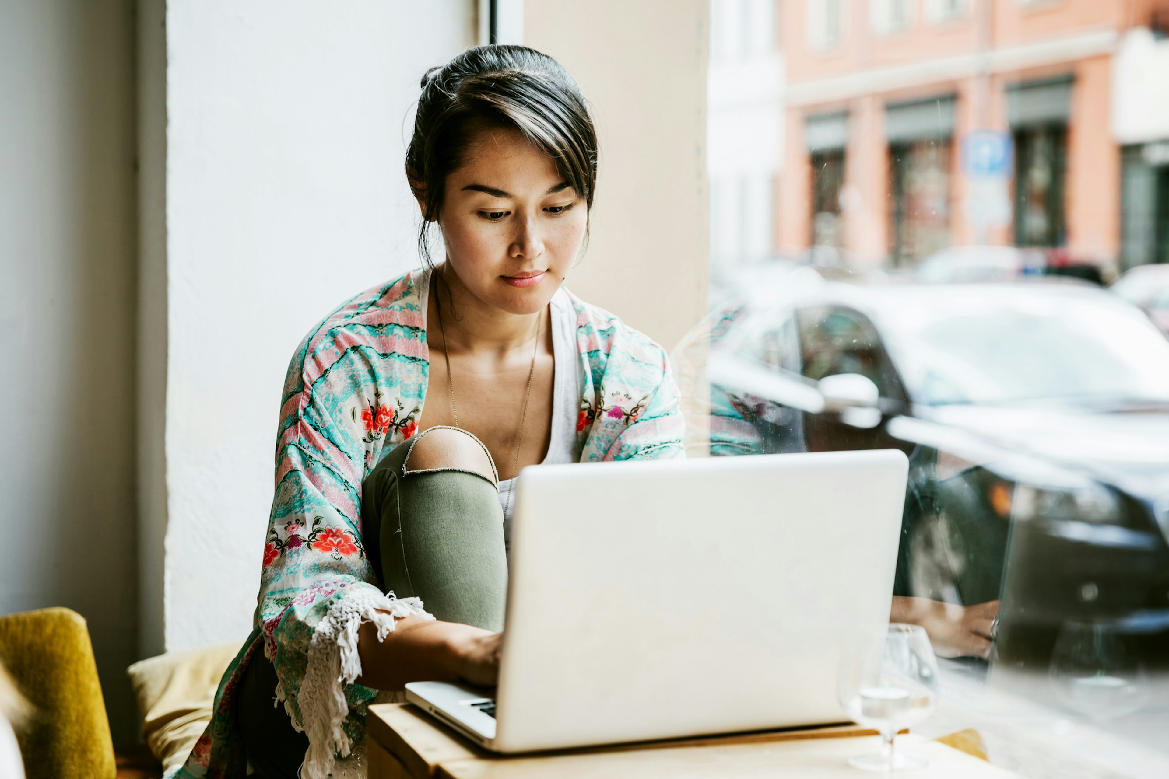 A woman works on her laptop in a coffeeshop.