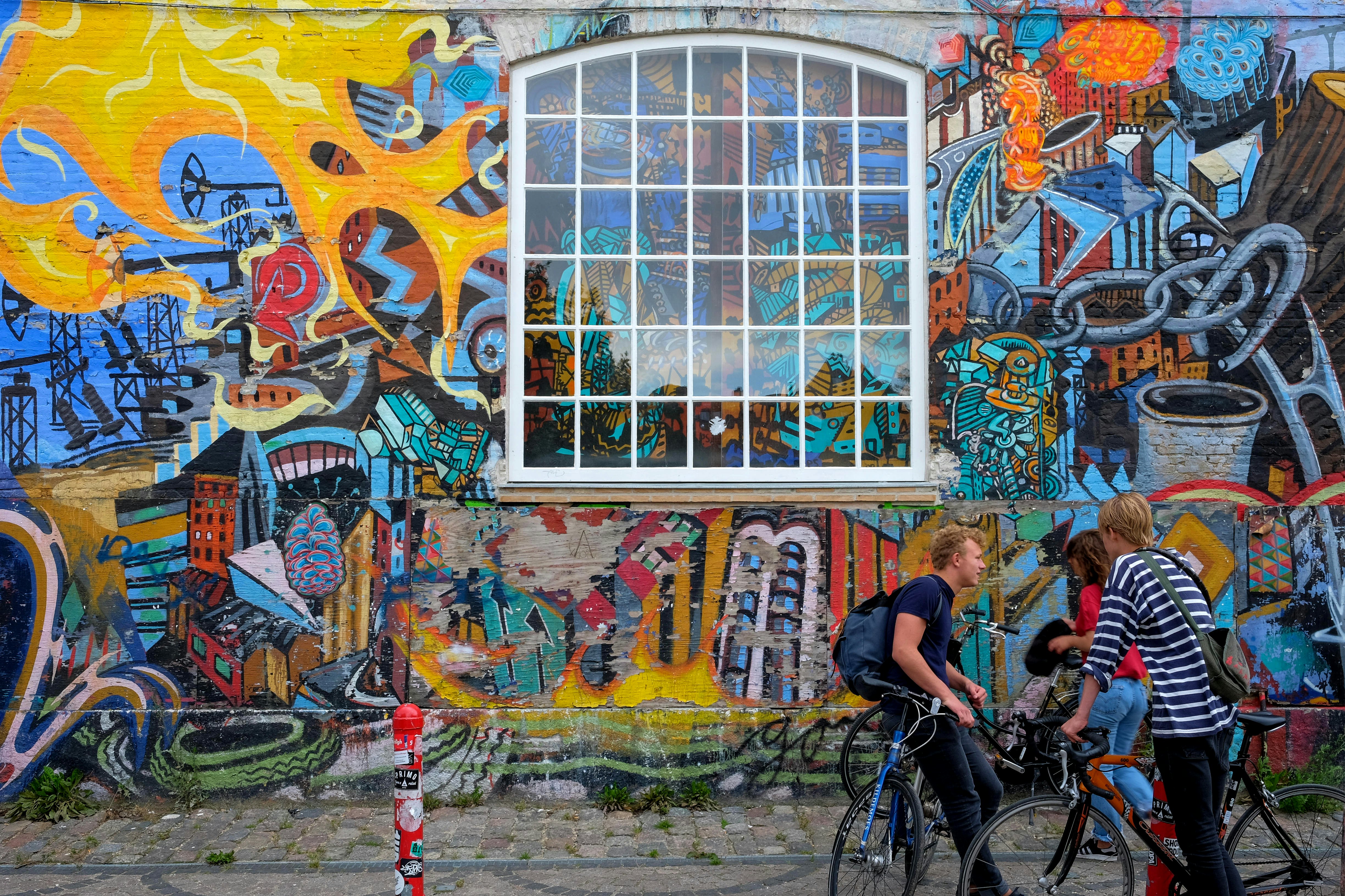 People with bikes in front of walls covered in colorful graffiti