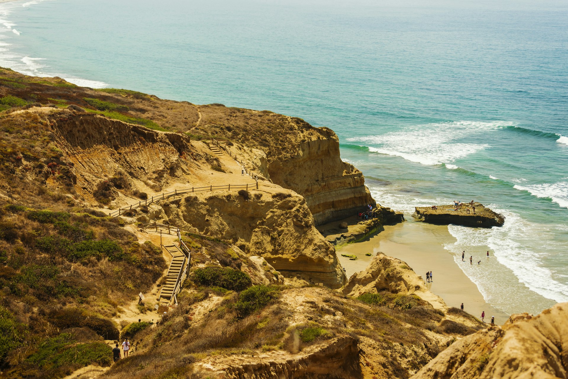 Sandy pathways and boardwalks lead alongside a cliff and down to a beach