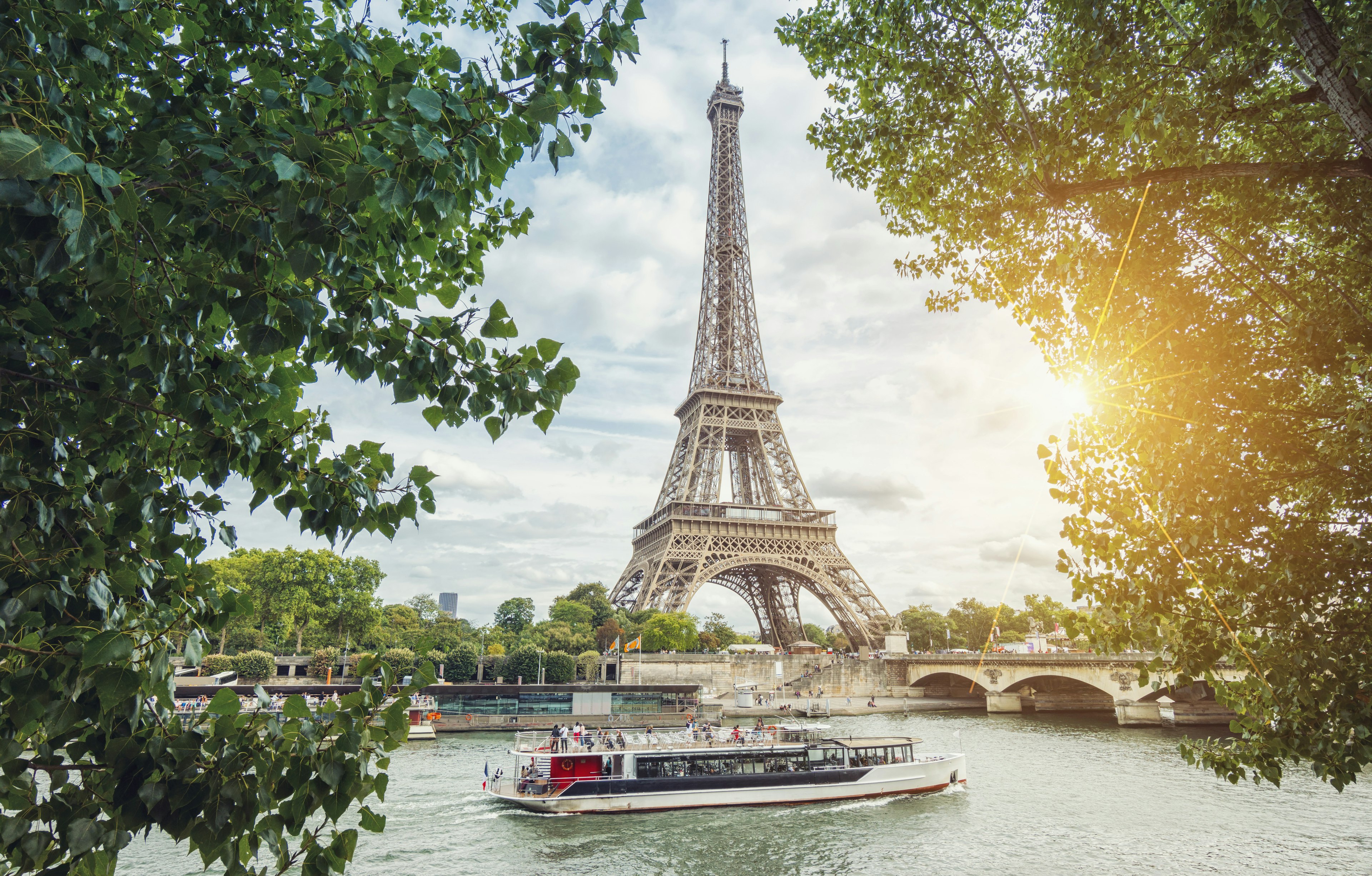 A river boat passes in front of the Eiffel Tower.