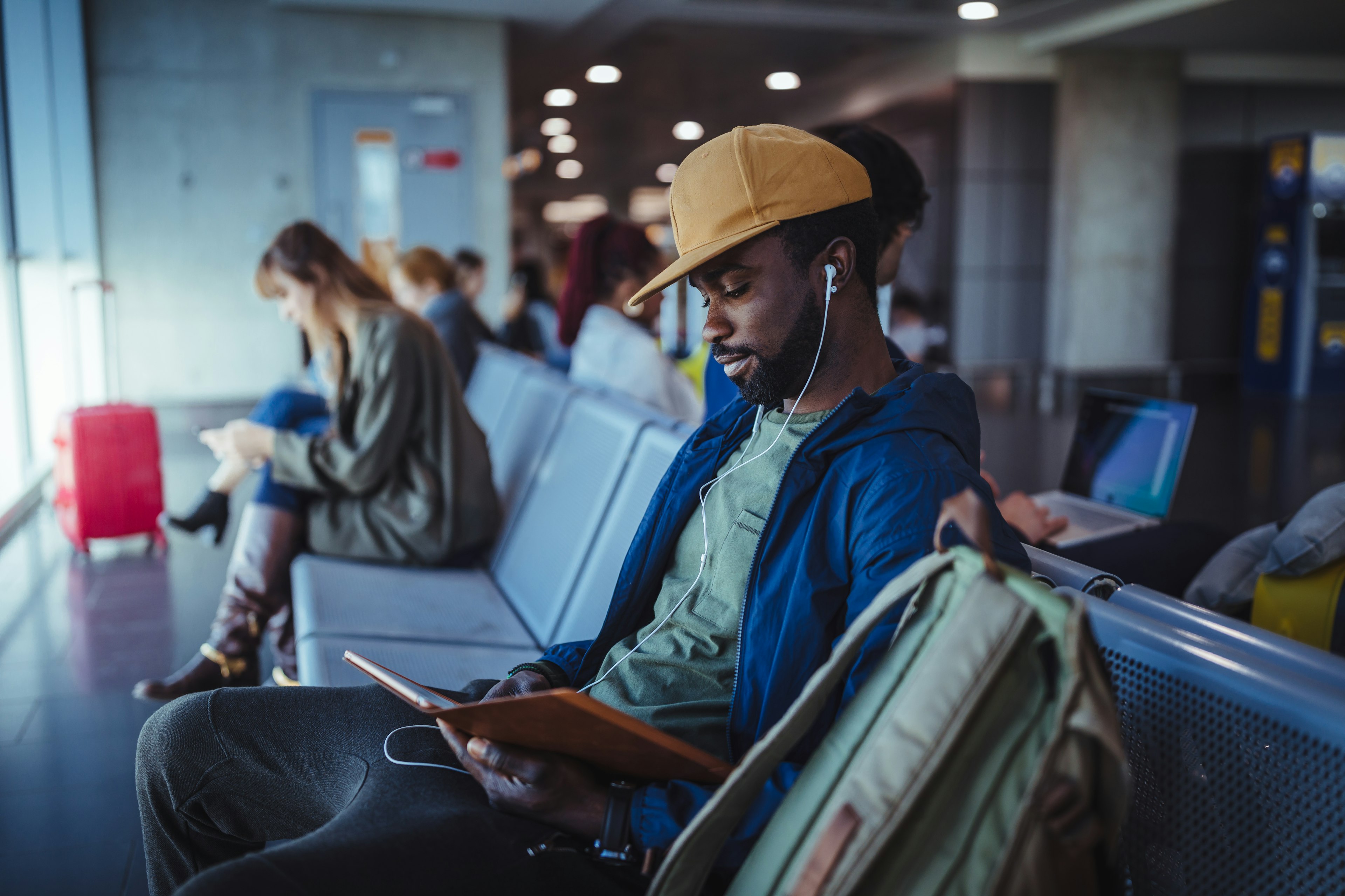 Multi-ethnic passengers sitting on bench and waiting at airport