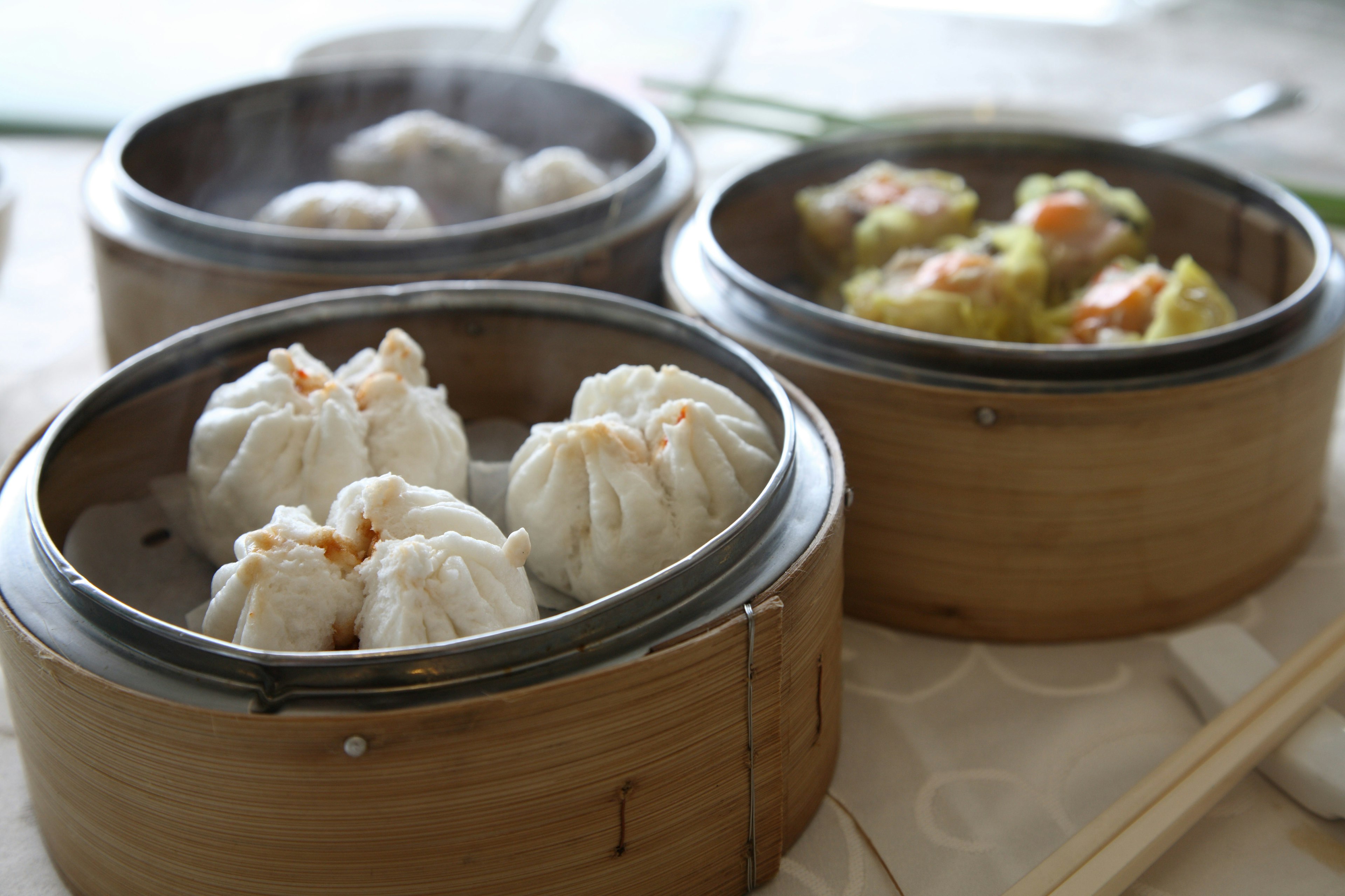 White steamed buns in three brown bamboo dishes