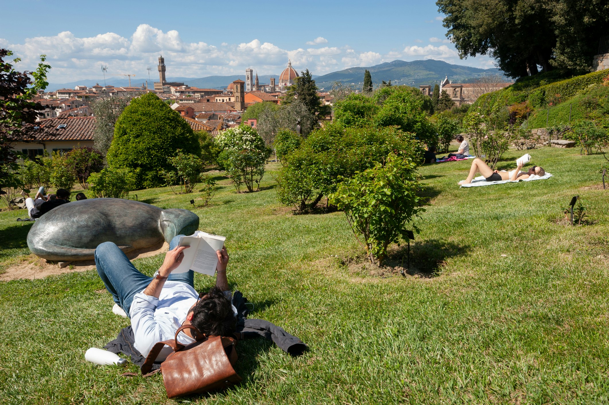 People sunbathing and reading books in Giardino delle Rose with views of Florence in the background