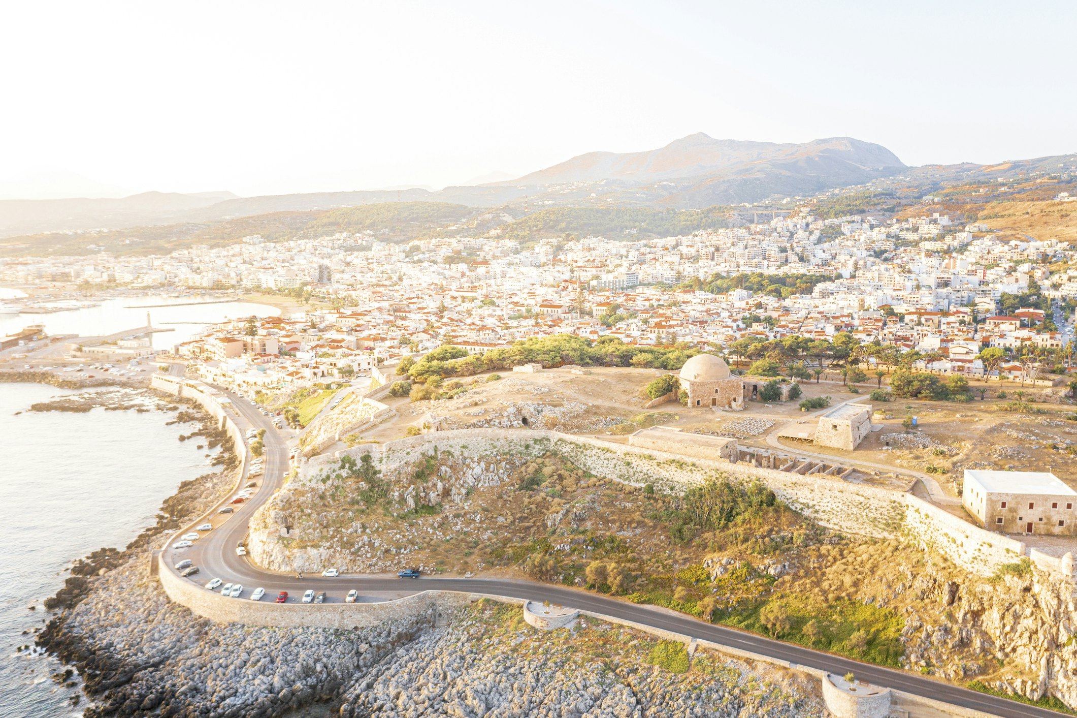 Aerial view of an old fortress on the hill with a road running along the coast