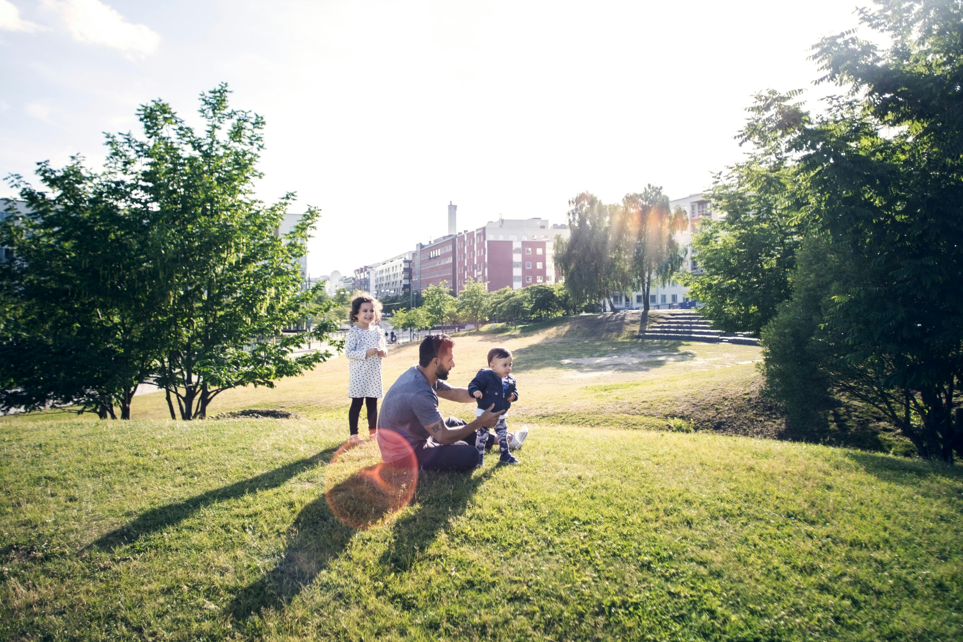 A father and two children sitting on the grass