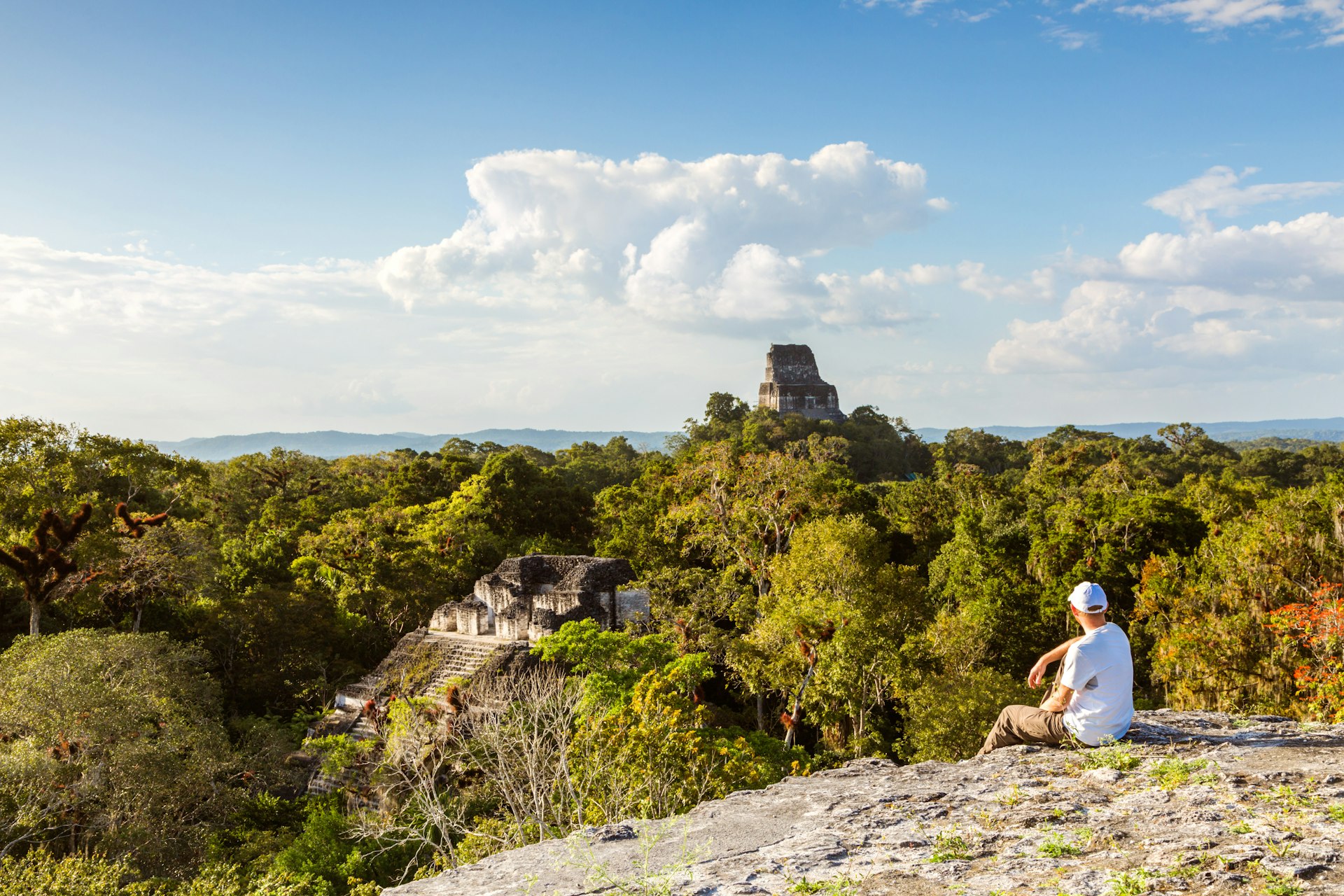 Tourist looking at old mayan ruins from high lookout (Temple IV and El Mundo Perdido), Tikal, Guatemala