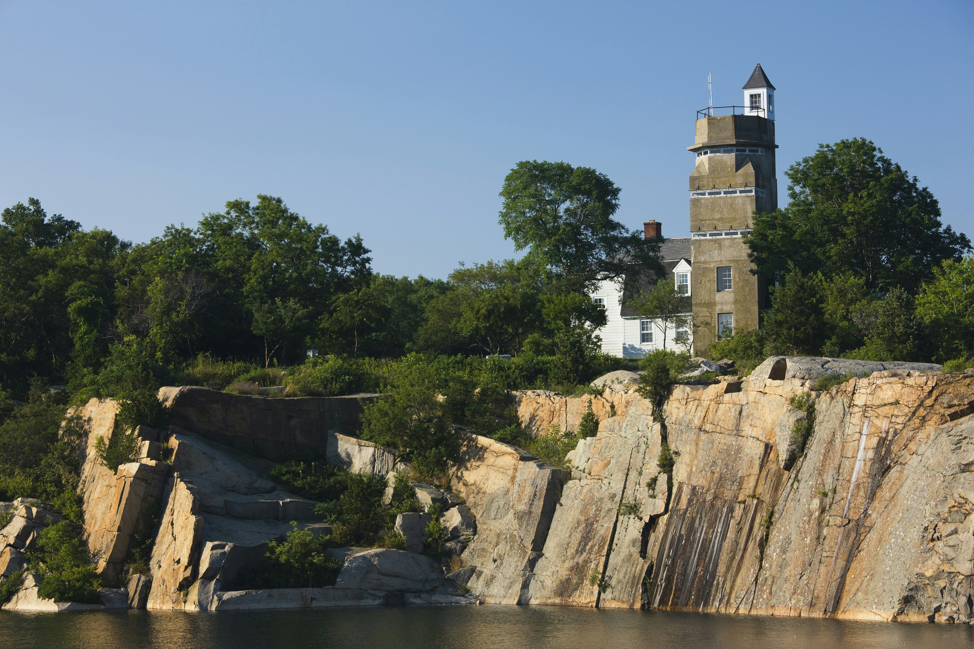 A WW2 submarine lookout tower and an old granite quarry above a body of water at Halibut Point State Park in Massachusetts.