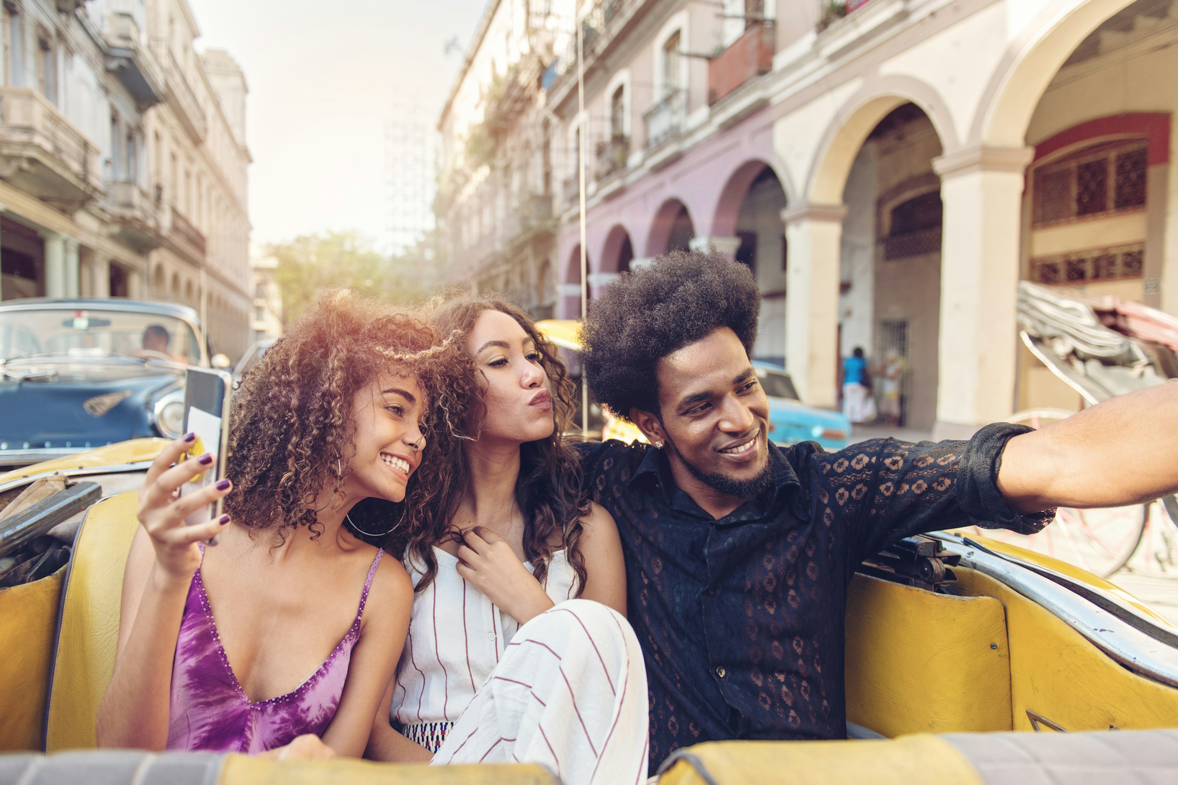 Three friends touring Havana in an old car