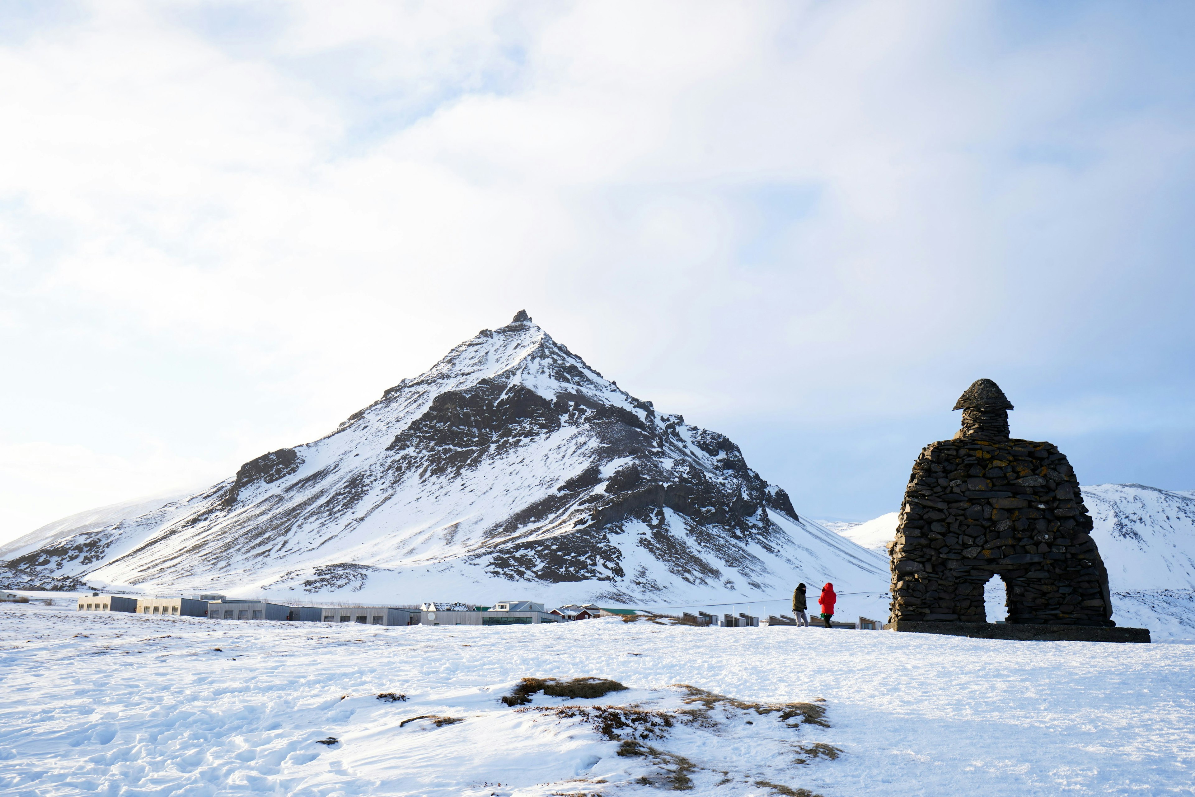 Two hikers approach a snow-covered peak