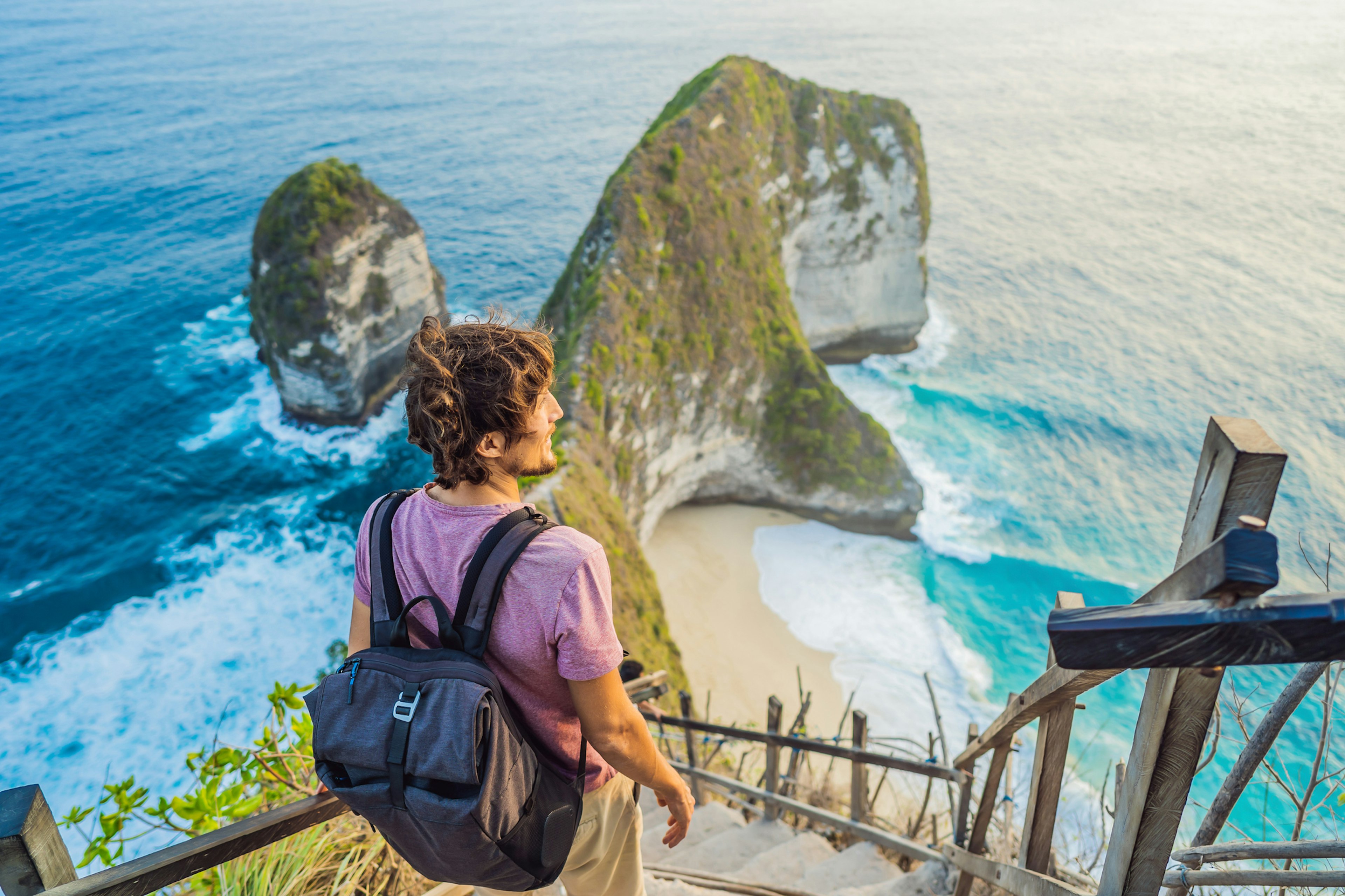 Man stand at viewpoint overlooking at beautiful Kelingking Beach on Nusa Penida Island Bali