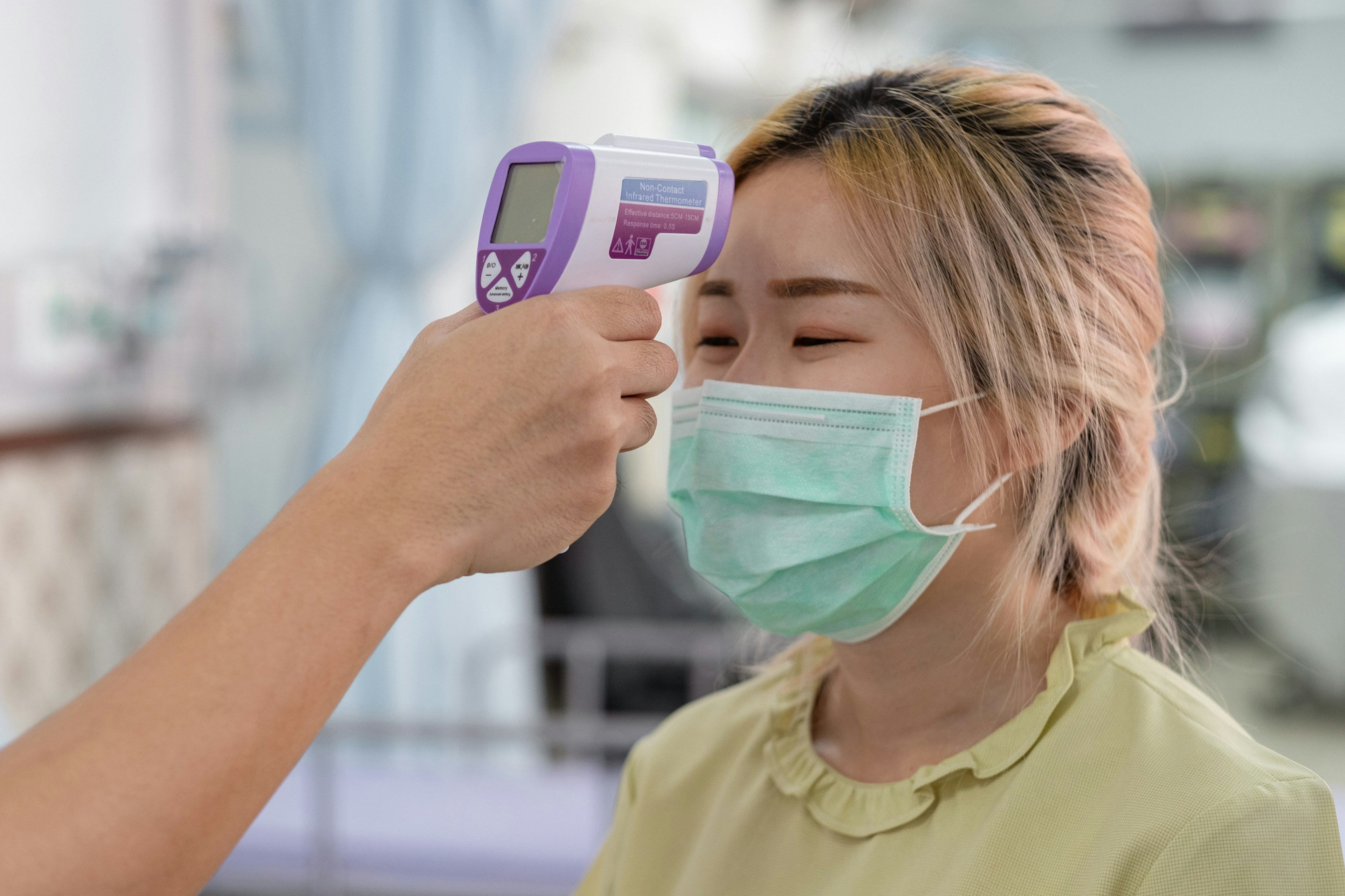 A temperature check being conducted via infrared thermometer