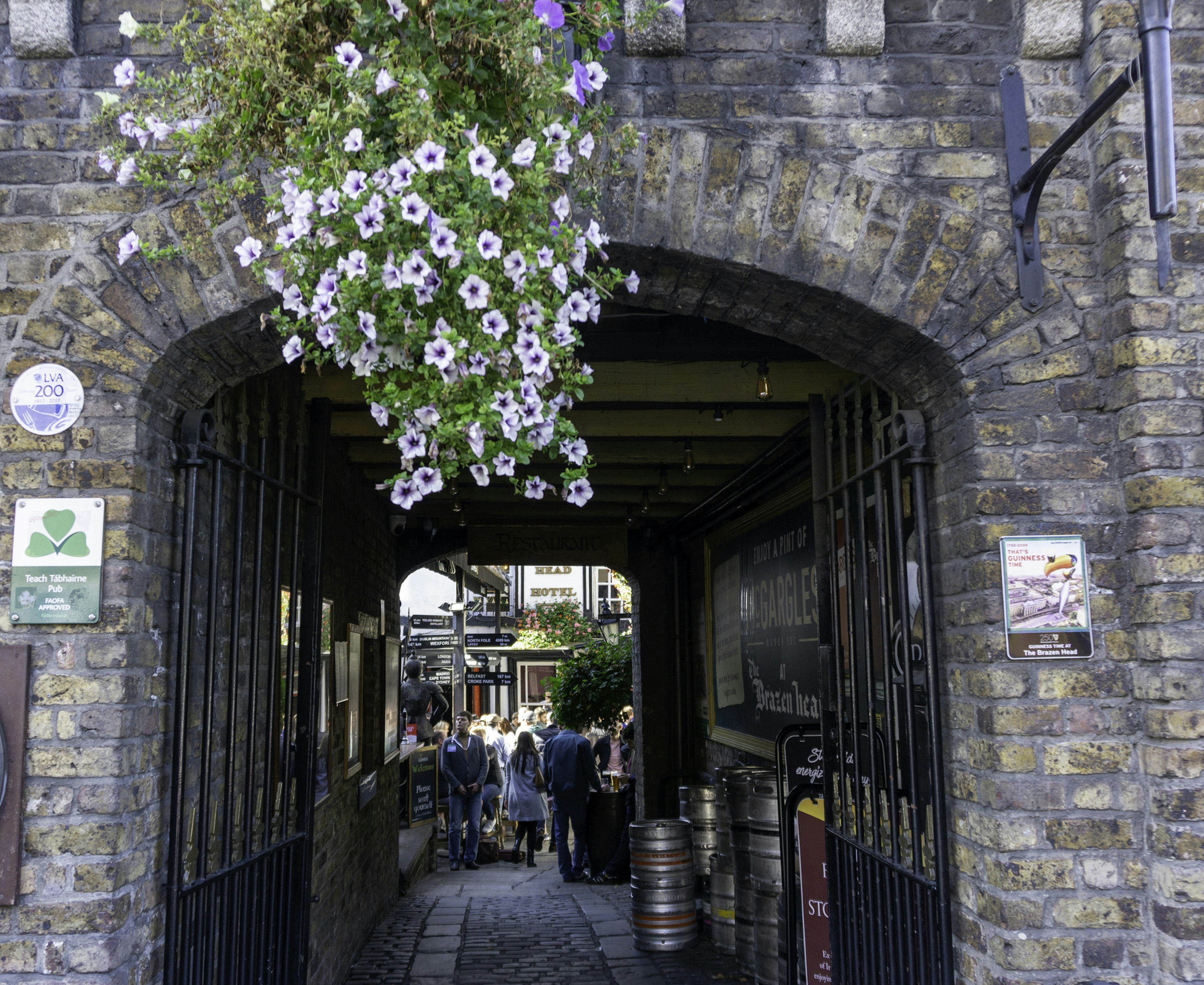 A shot through an arched stone doorway into the courtyard of a pub where people are gathered