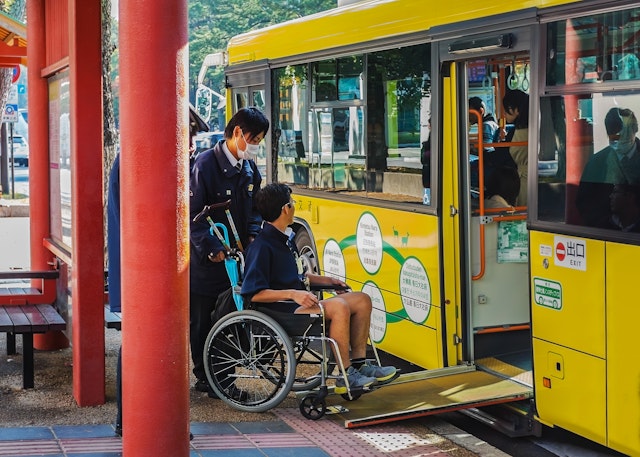 A man in a wheelchair is helped onto a bus, via a temporary ramp, in Nara, Japan.