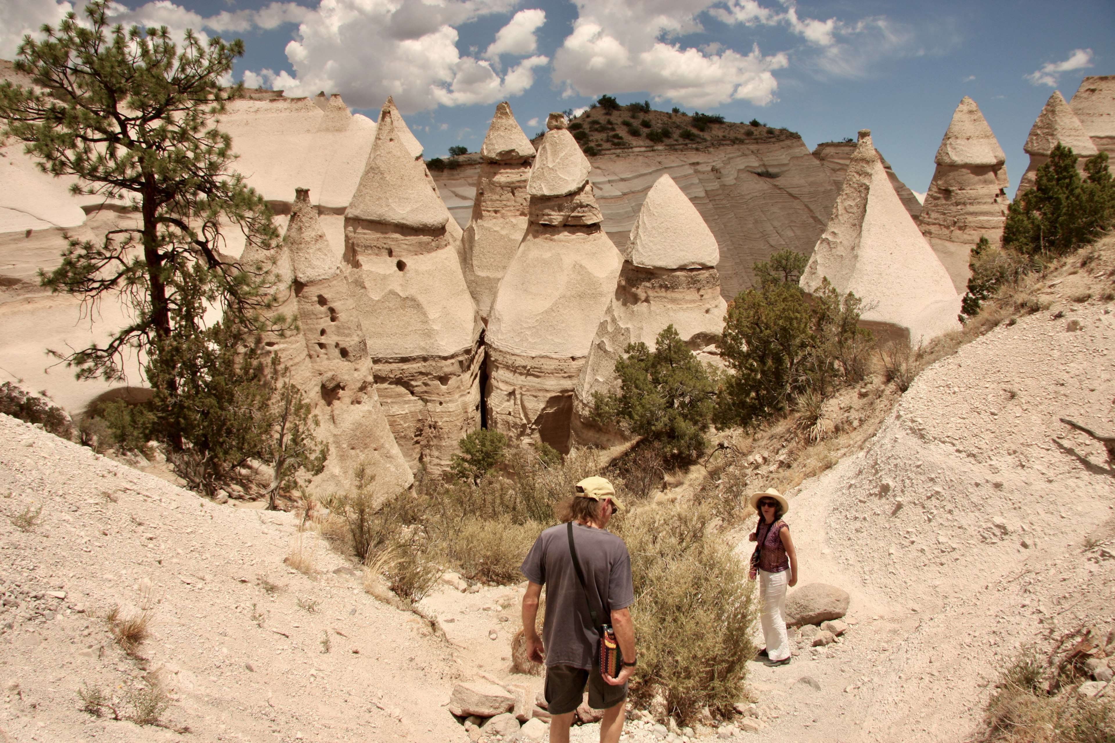 A man and a woman hike a trail among the pointy rock formations at the Kasha-Katuwe Tent Rocks National Monument, New Mexico