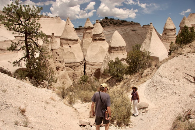 A man and a woman hike a trail among the pointy rock formations at the Kasha-Katuwe Tent Rocks National Monument, New Mexico