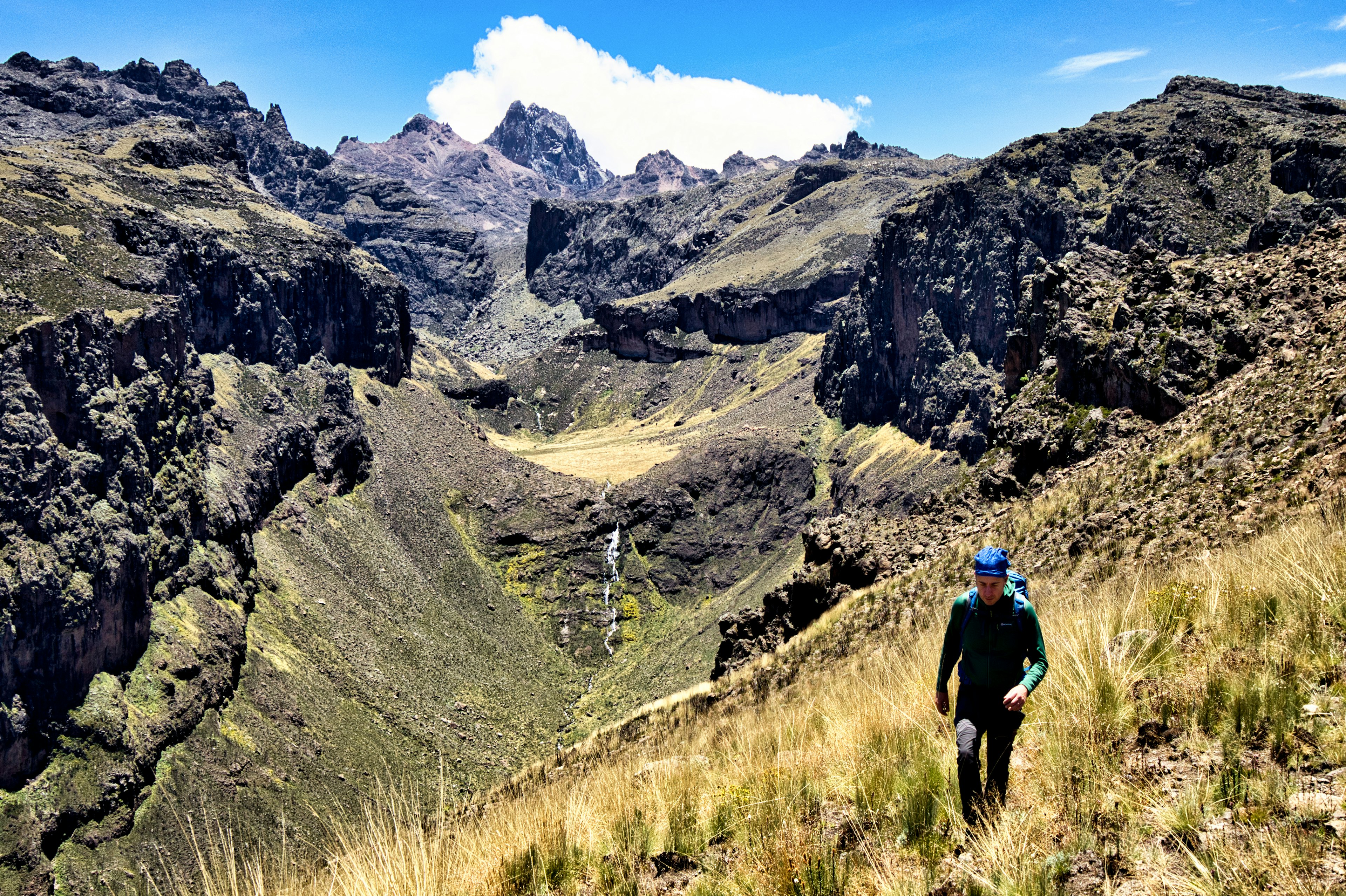 Peter Elia hikes with Nithi Waterfall behind him on the slopes of Mt Kenya