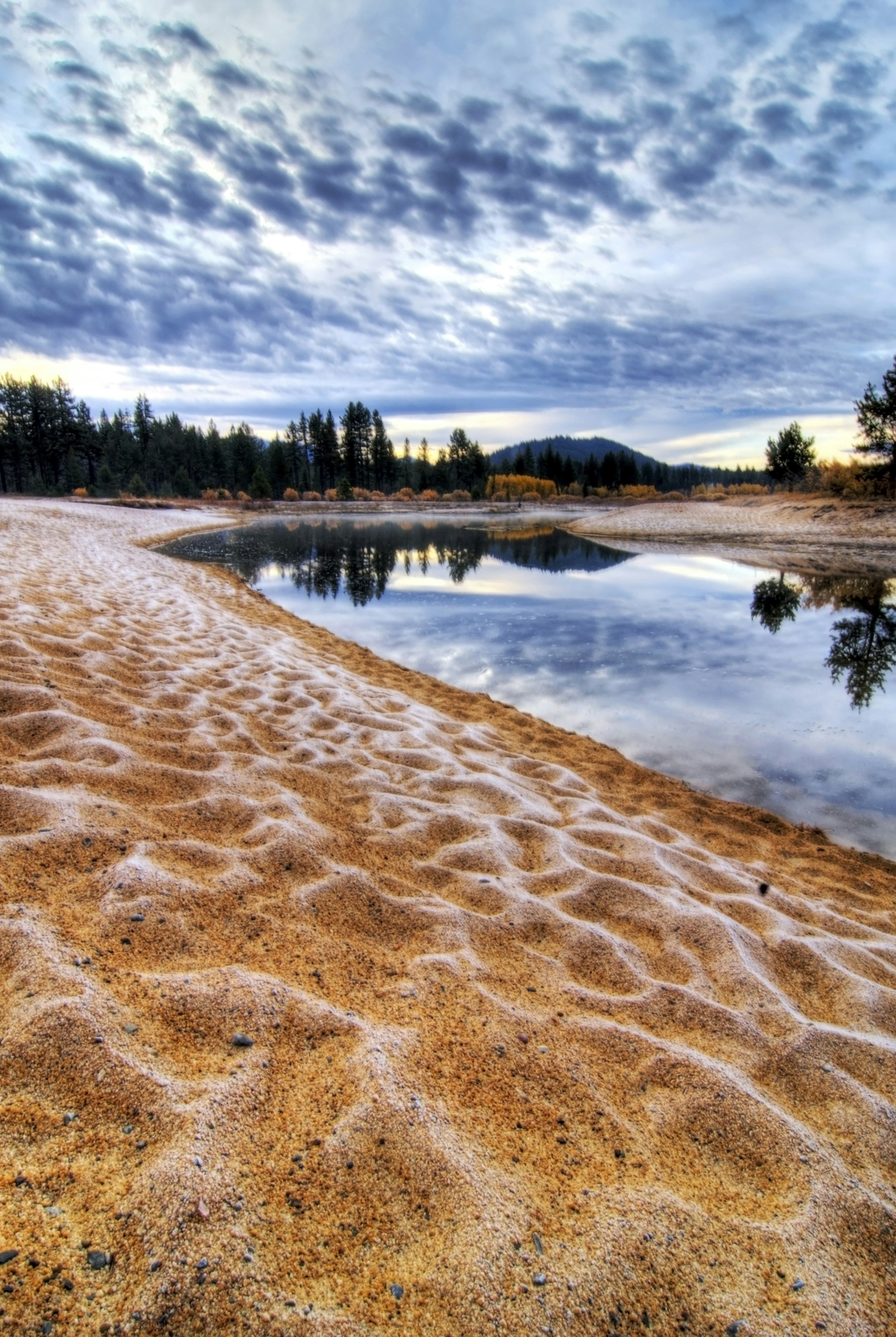 The sun rises over a bay, where the golden sand is rippled and encrusted with light frost.