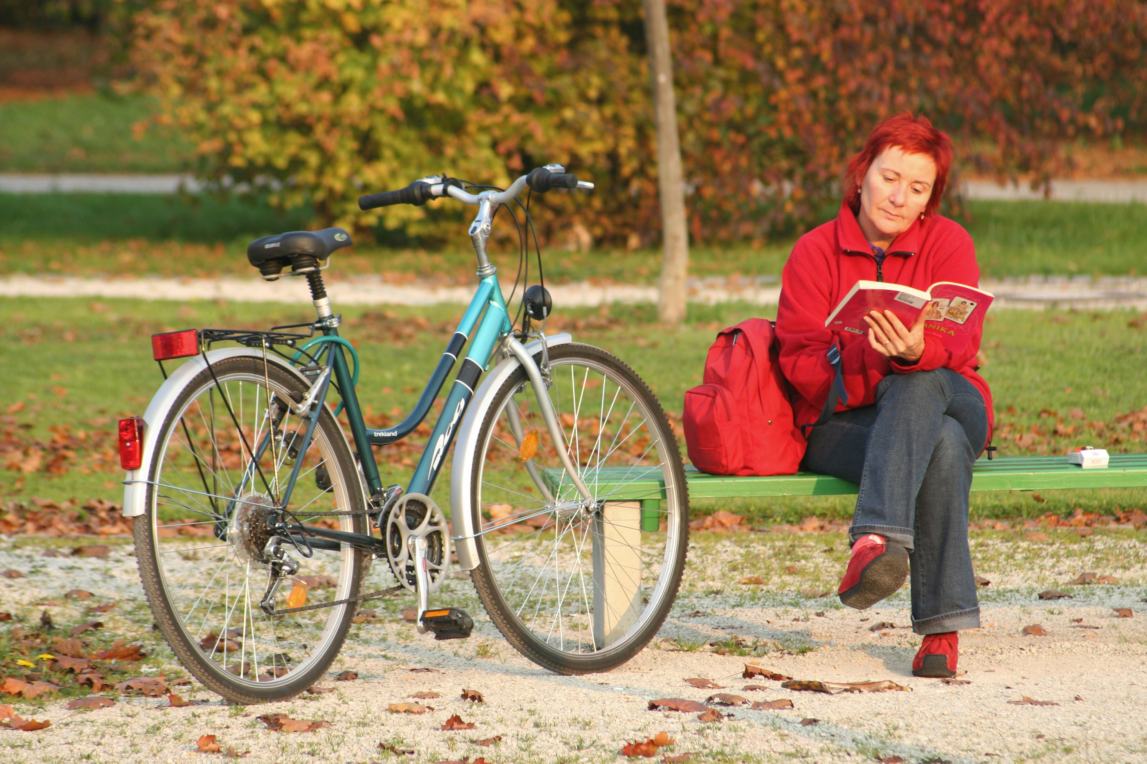 A woman with a bike reading at a bench in Park Tivoli, Ljubljana, Slovenia.