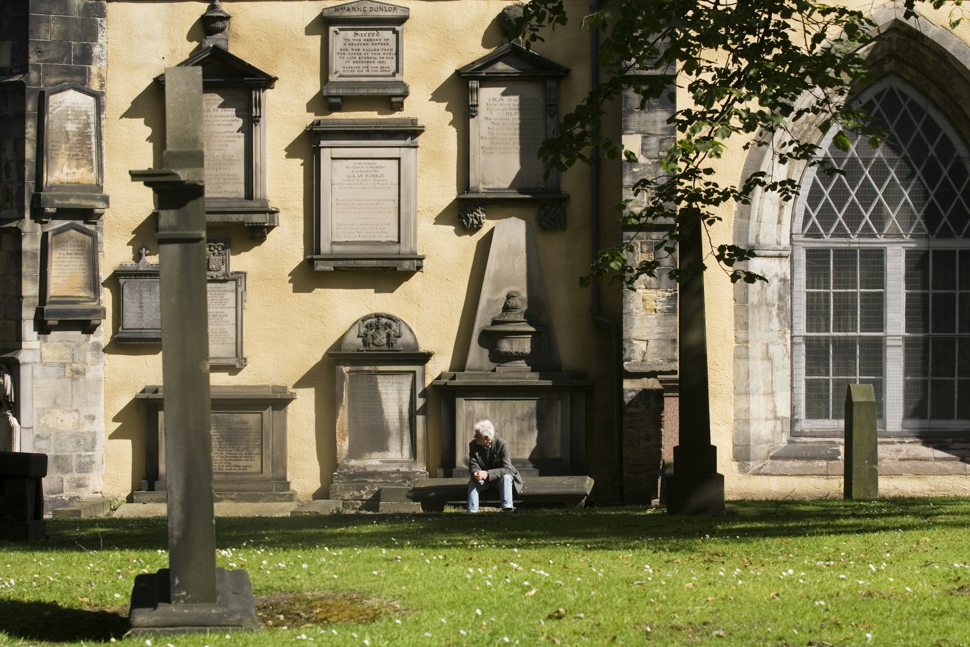 A man rests on a bench in the Greyfriars Kirkyard.