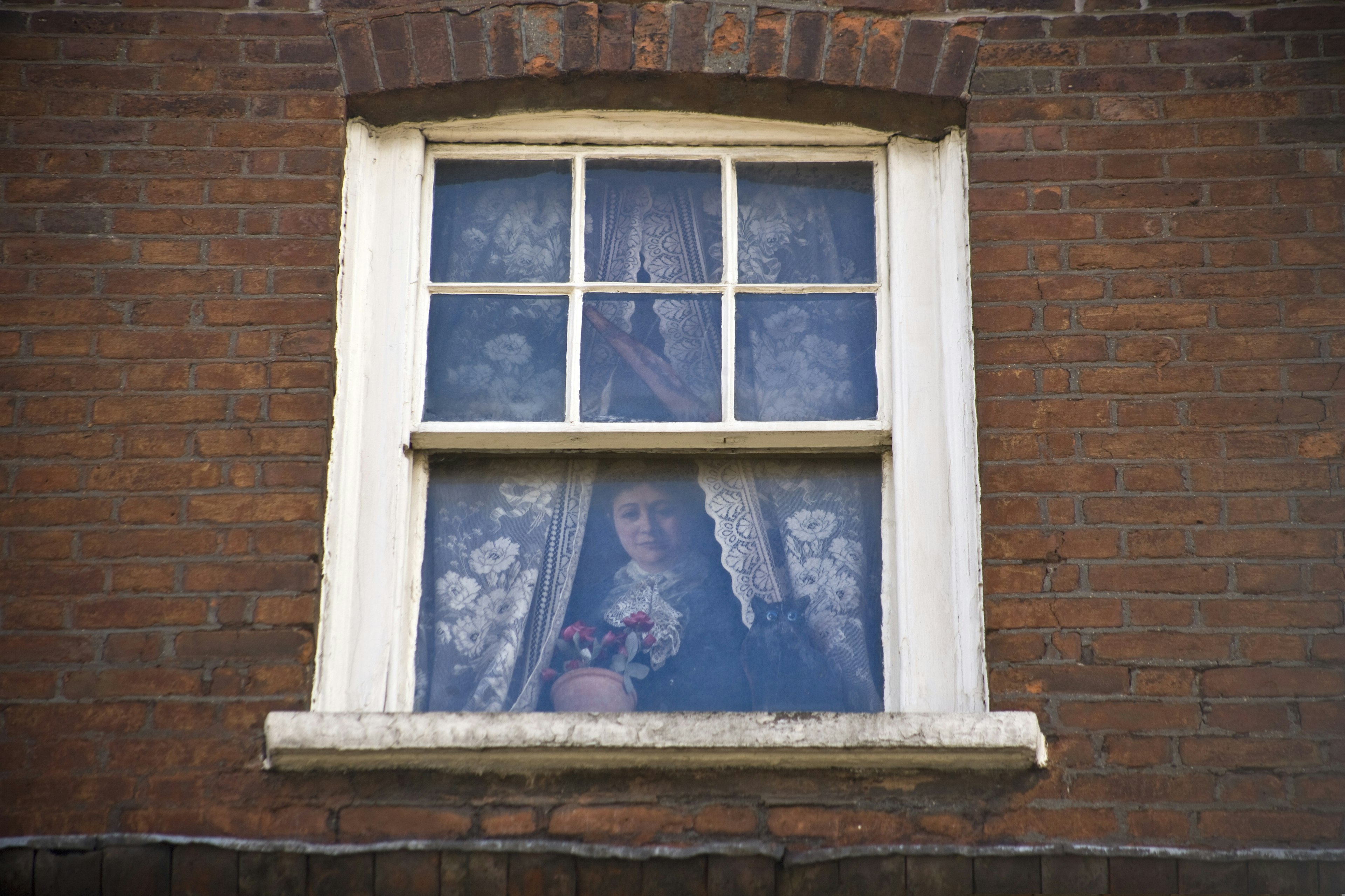 A woman is pictured in a trompe l'oeil window in London.