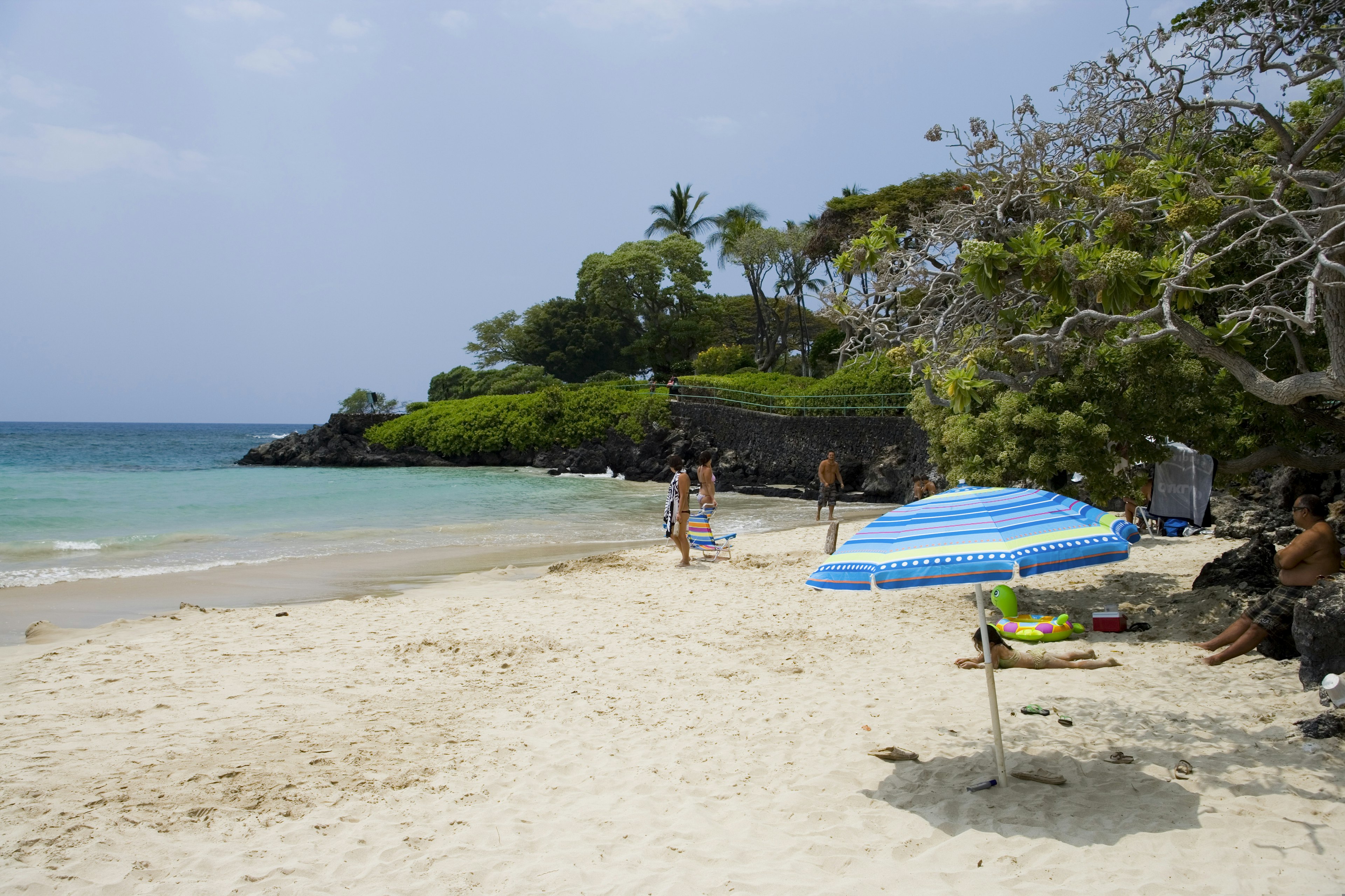 Families play in the calm waters of a white-sand beach