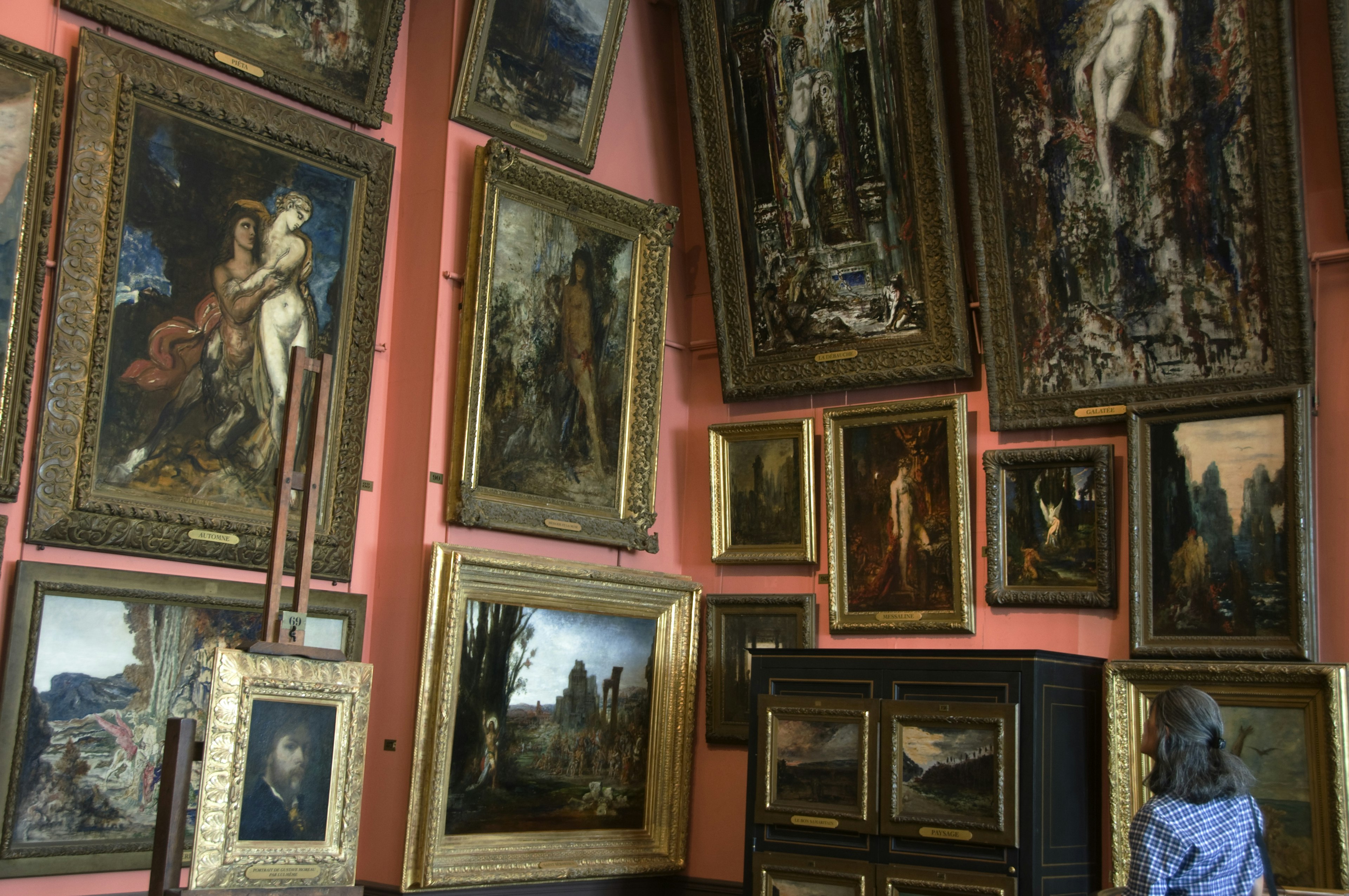 A visitor looks at paintings hanging in the Musée National Gustave Moreau, Paris, France