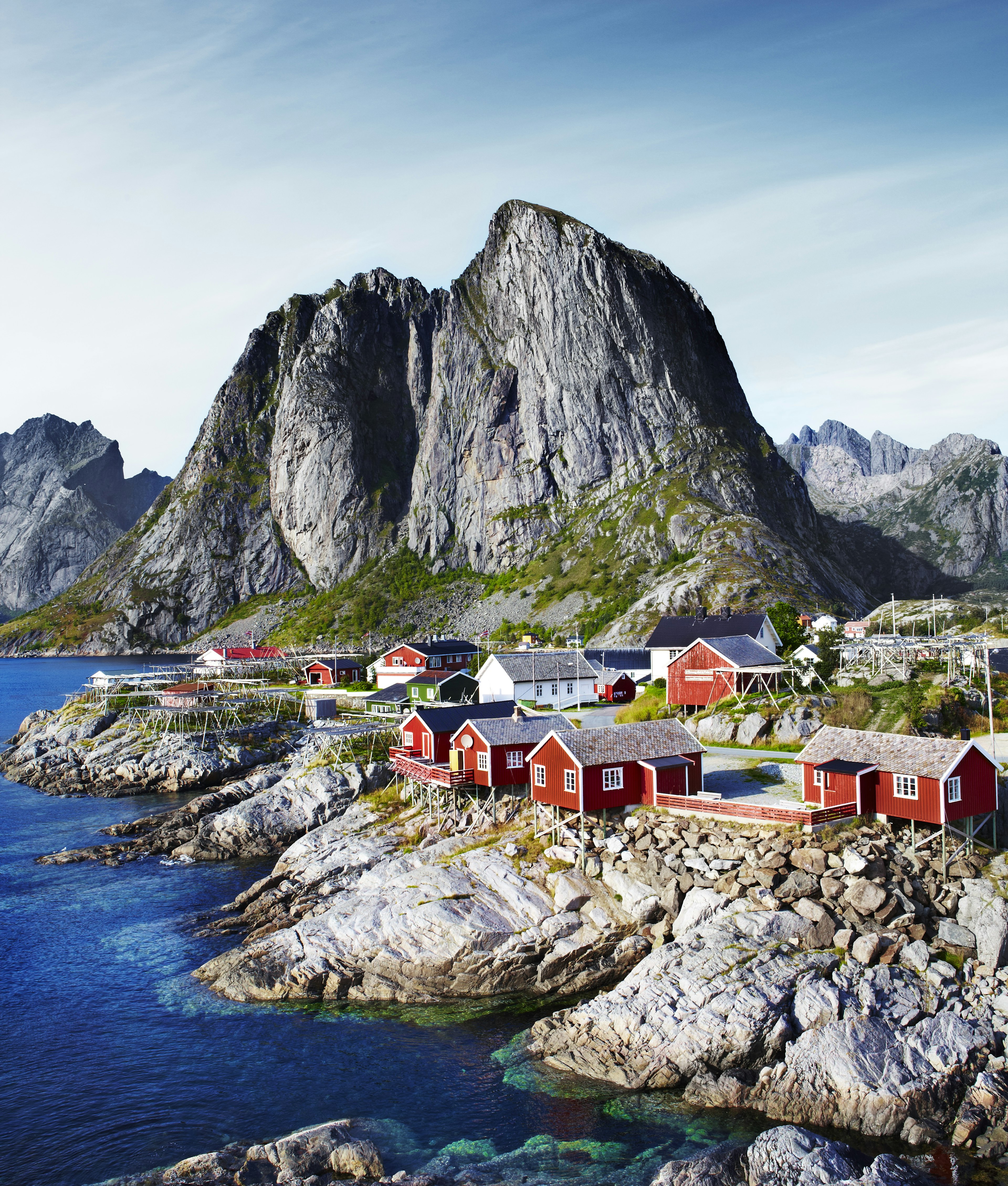 A mountain looms over red-paneled fisher huts