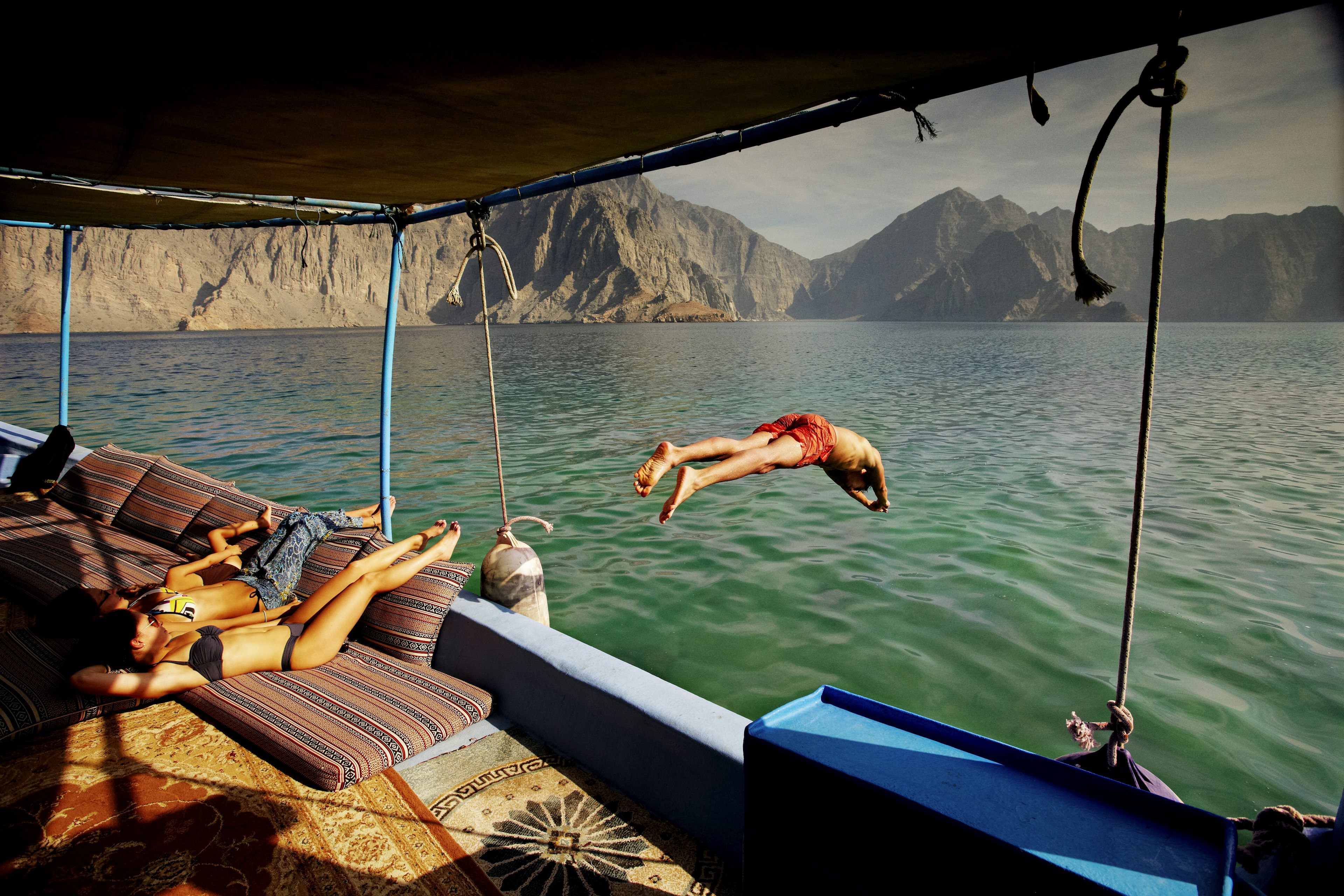 Man diving off tour boat cruising Musandam Coast in Oman