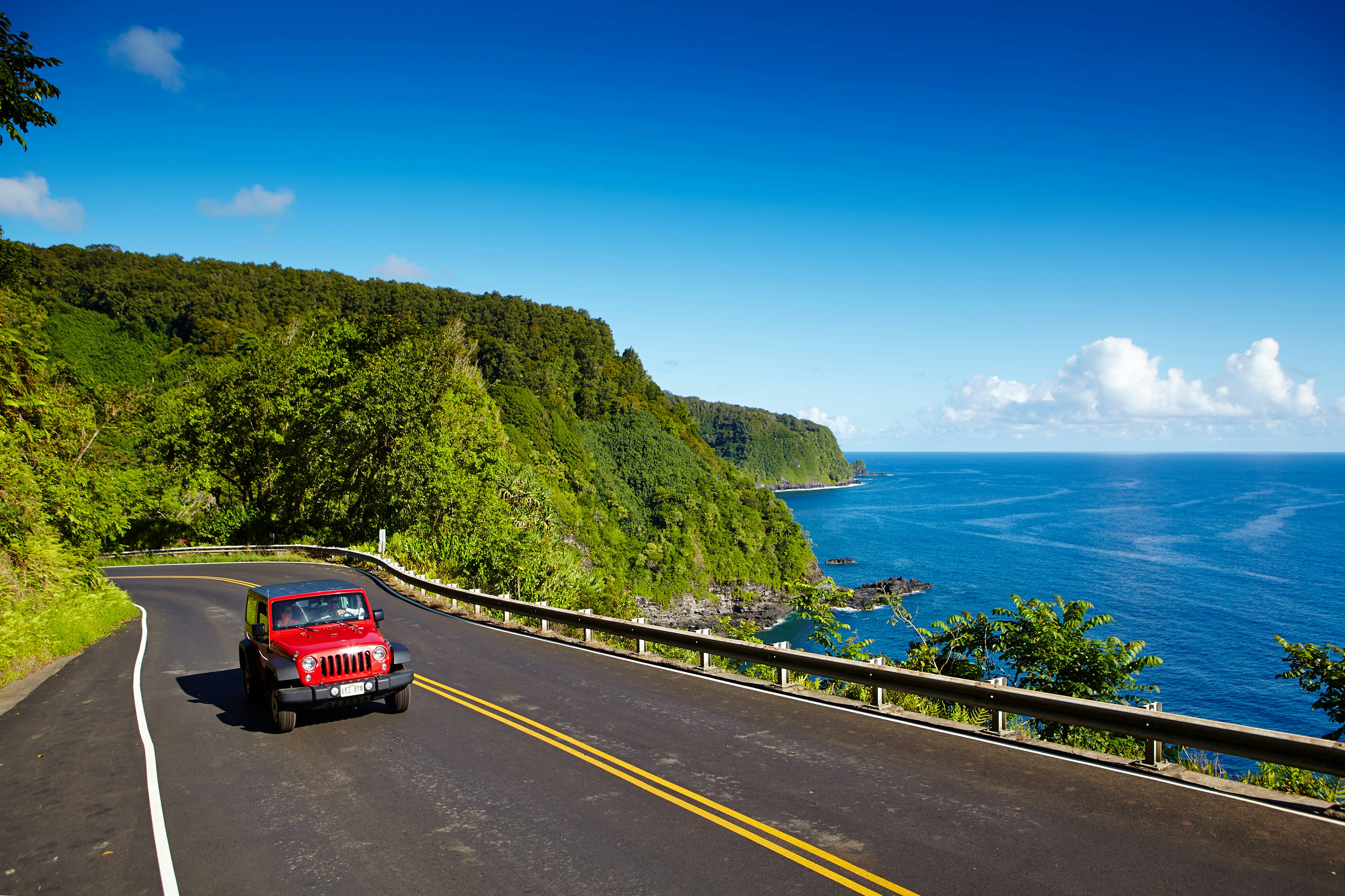 A red car on a coastal highway