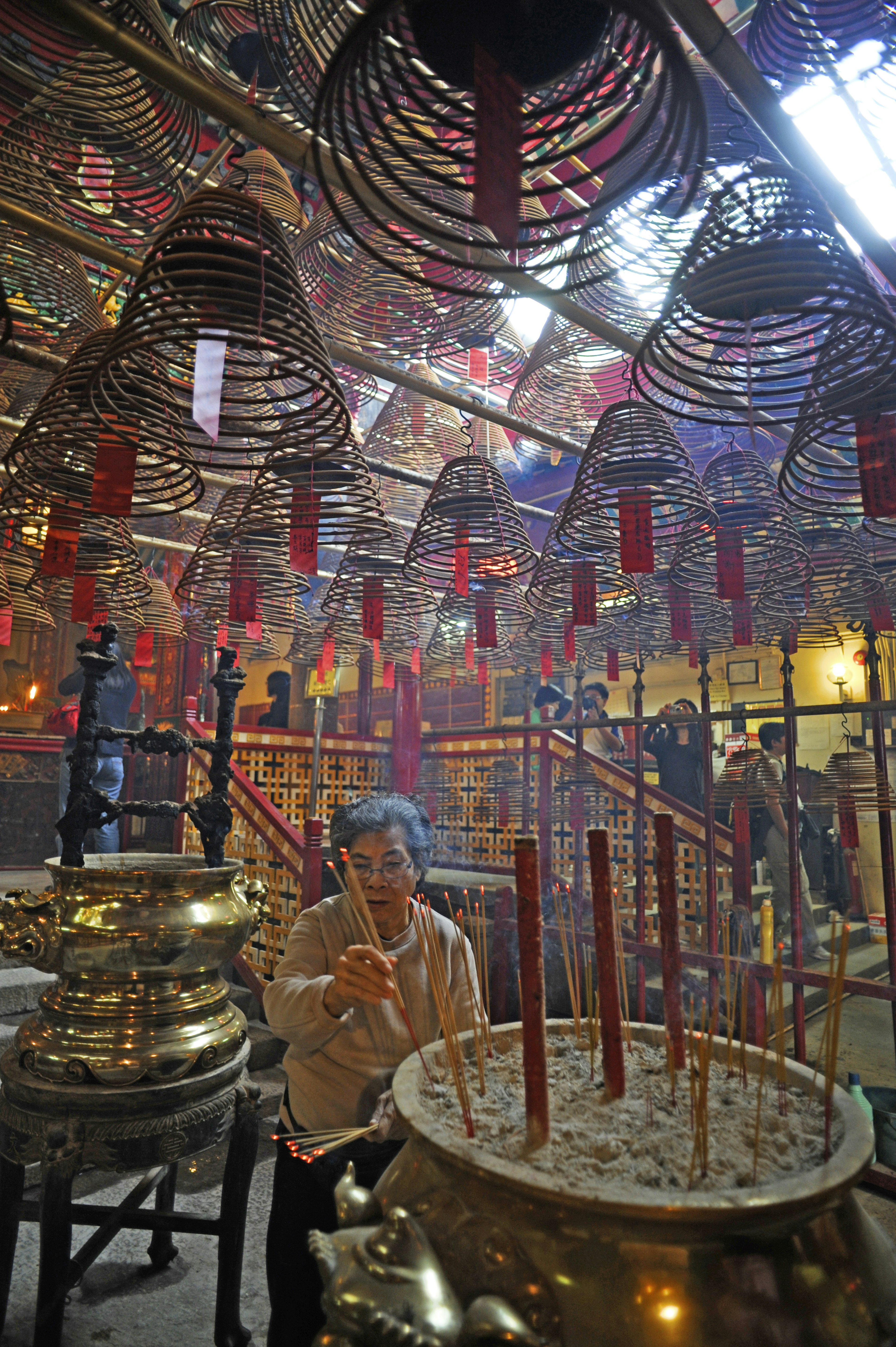 Woman placing incense sticks at Man Mo Temple