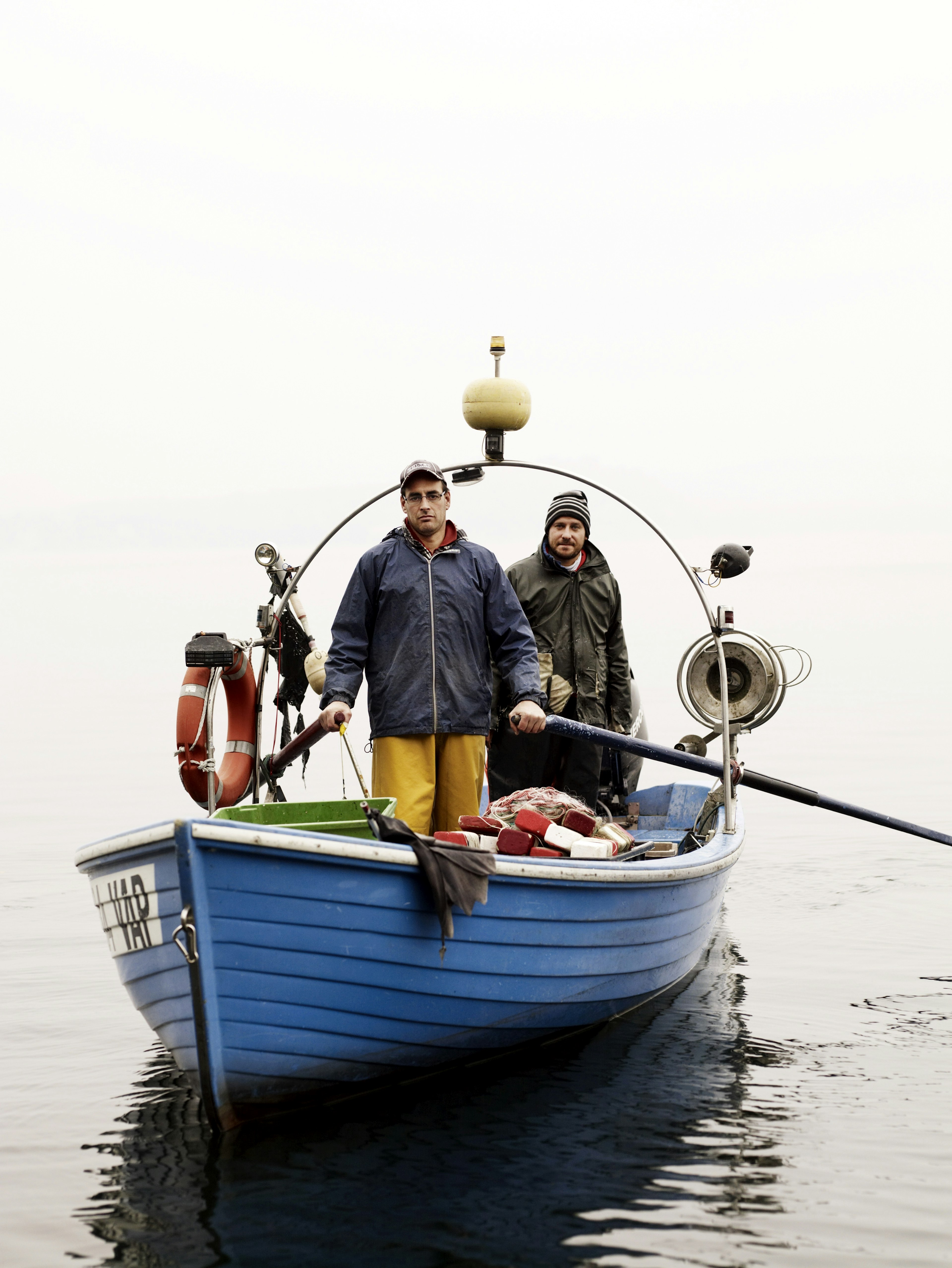 Two fishers in a blue boat on a cloudy lake